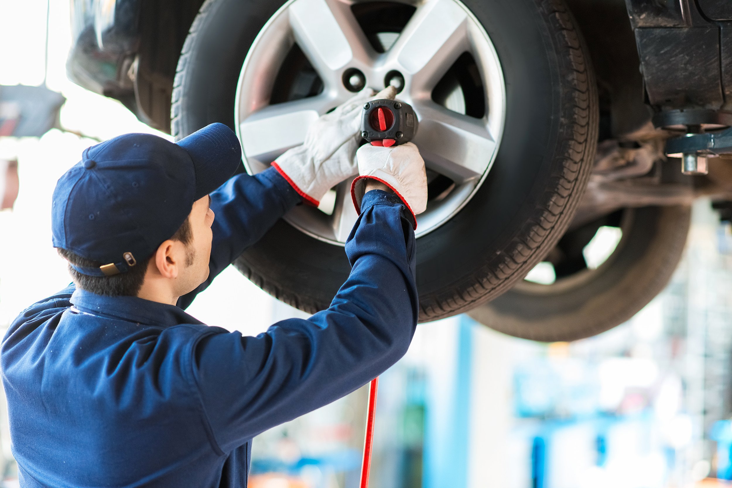 mechanician changing car wheel in auto repair shop