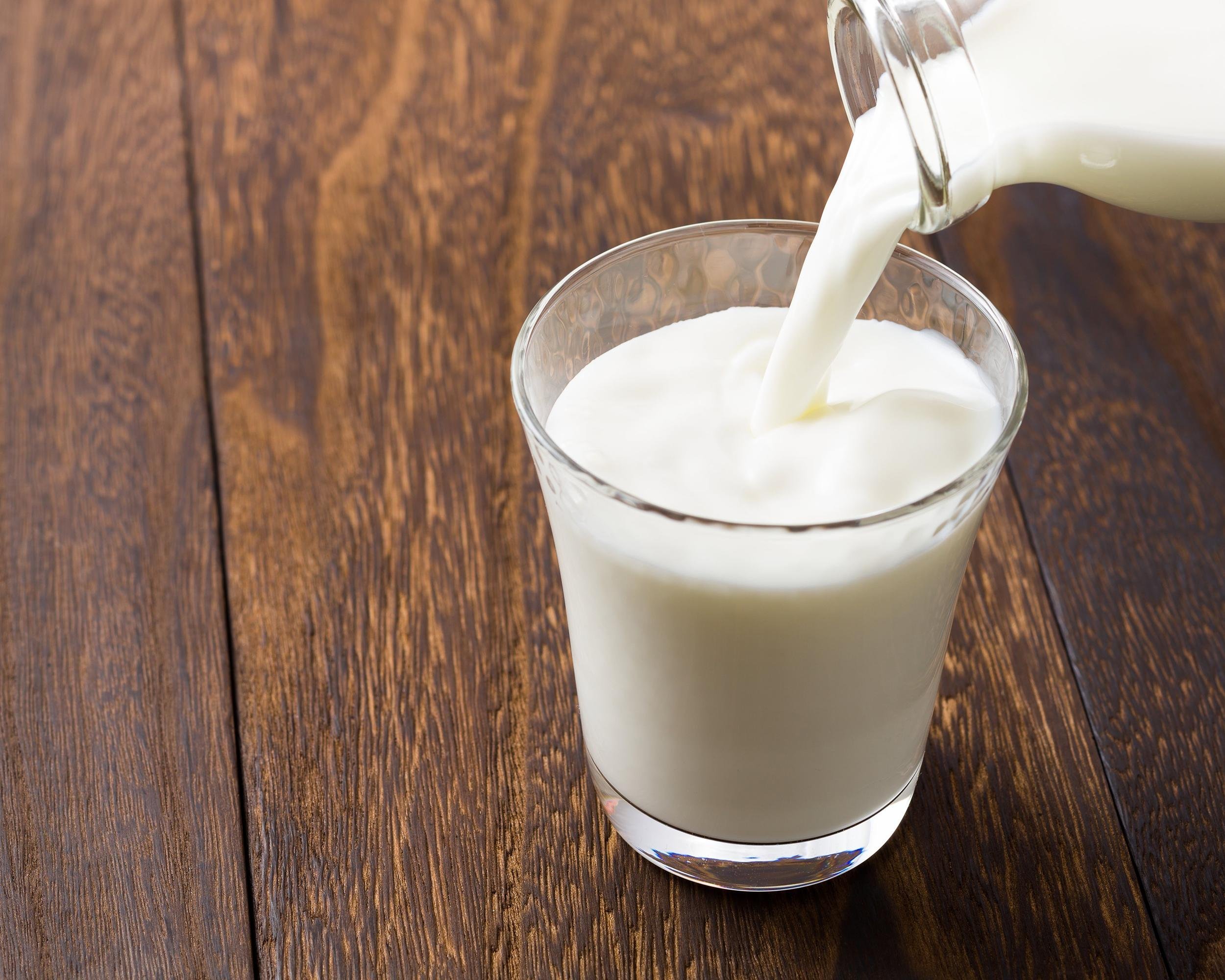 pouring milk into glass on wooden table