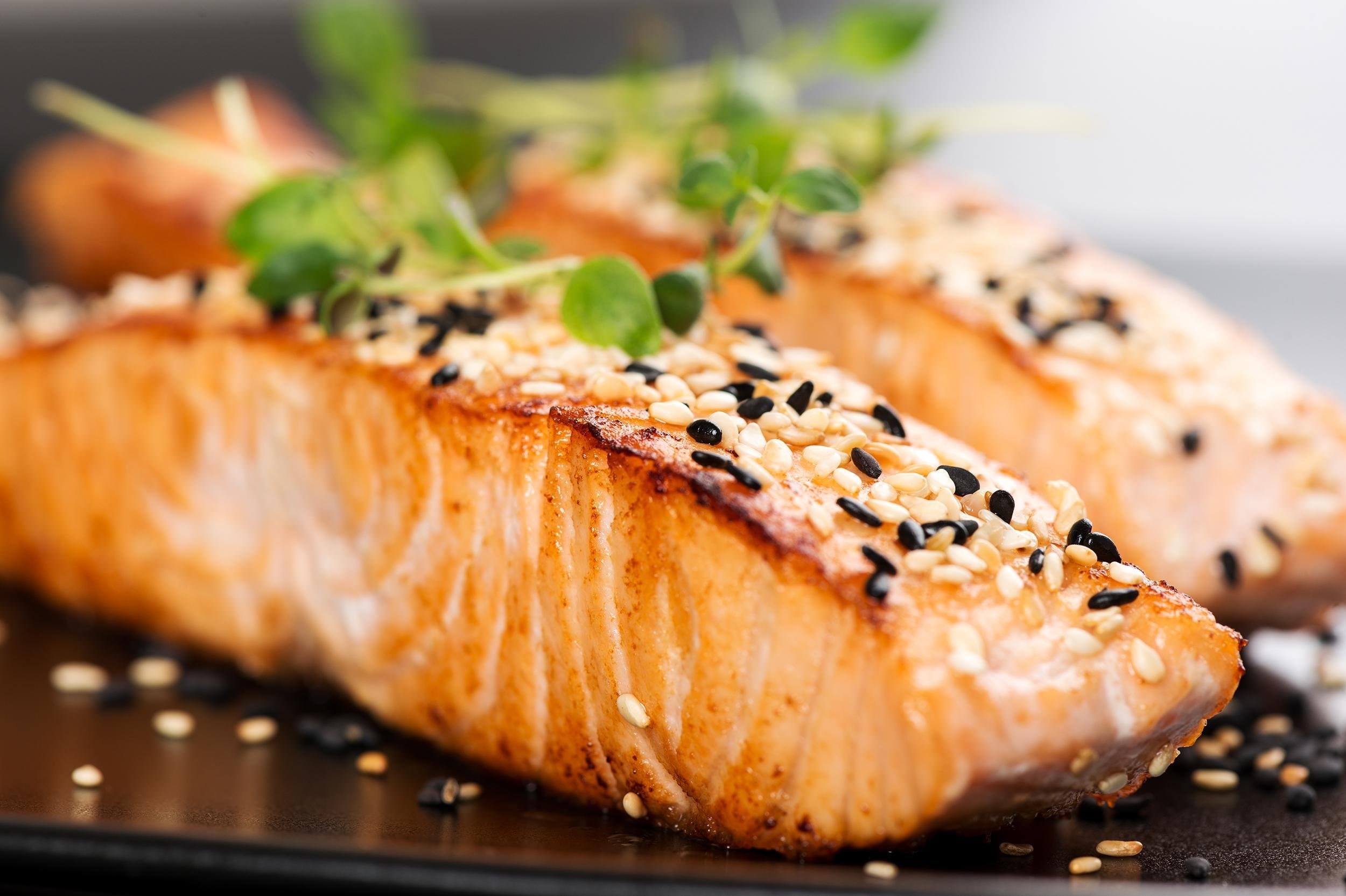 grilled salmon, sesame seeds and marjoram on a black plate