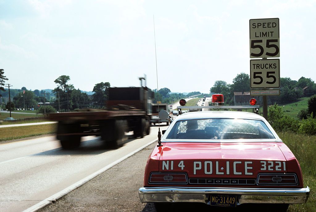 1970s POLICE CAR WITH RADAR GUN CHECKING FOR SPEEDERS IN 55 MPH SPEED ZONE