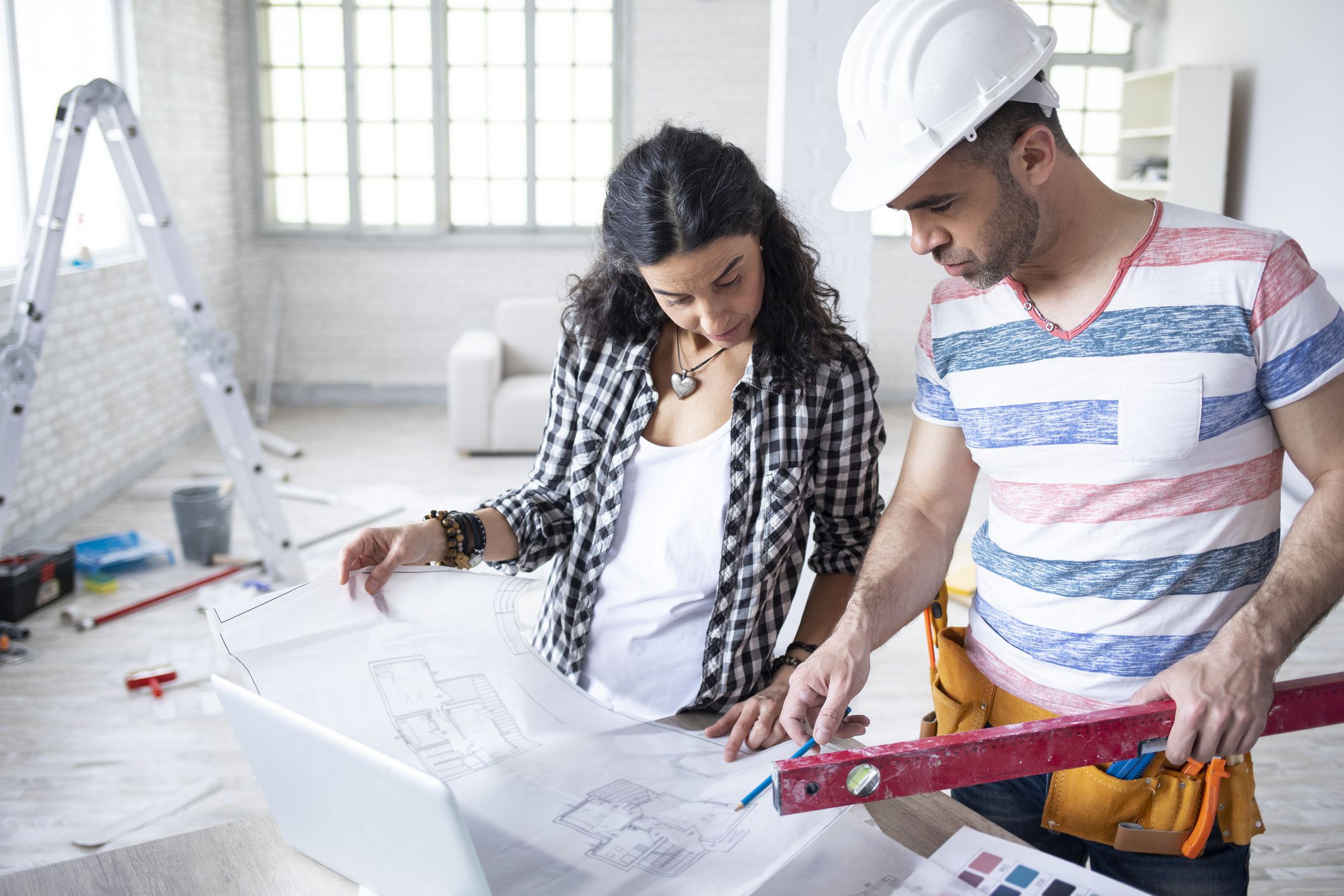 Woman discussing ideas with construction worker, in new apartment.