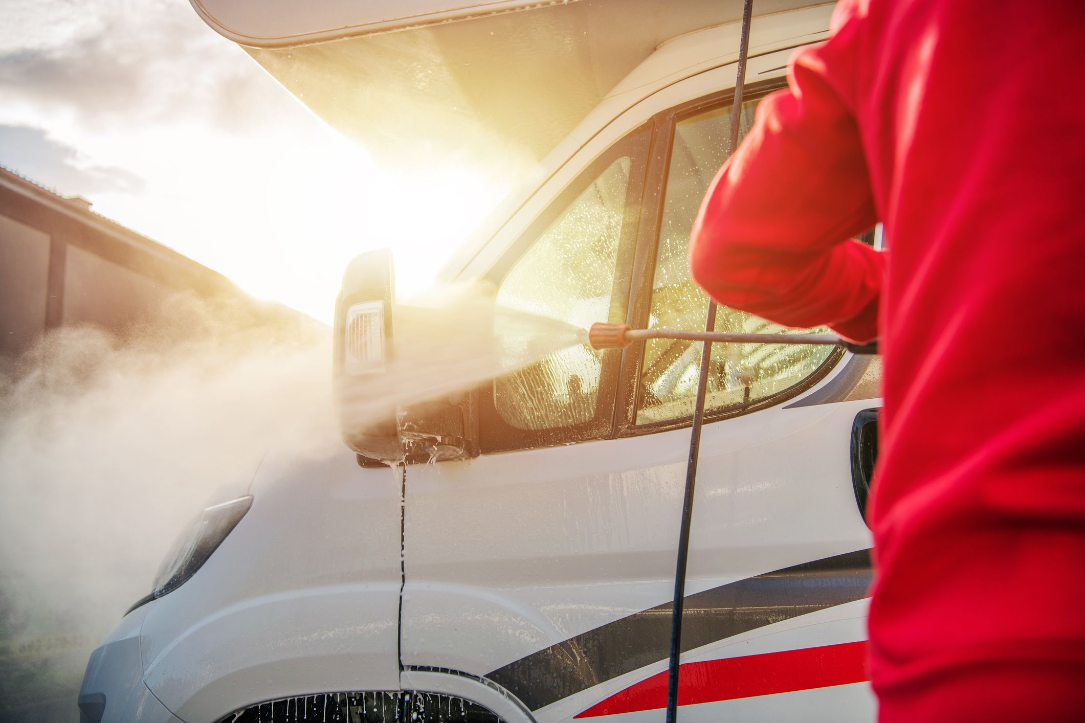 Caucasian Men Washing Camper Van RV Using Pressure Washer. After Season Motorhome Maintenance.