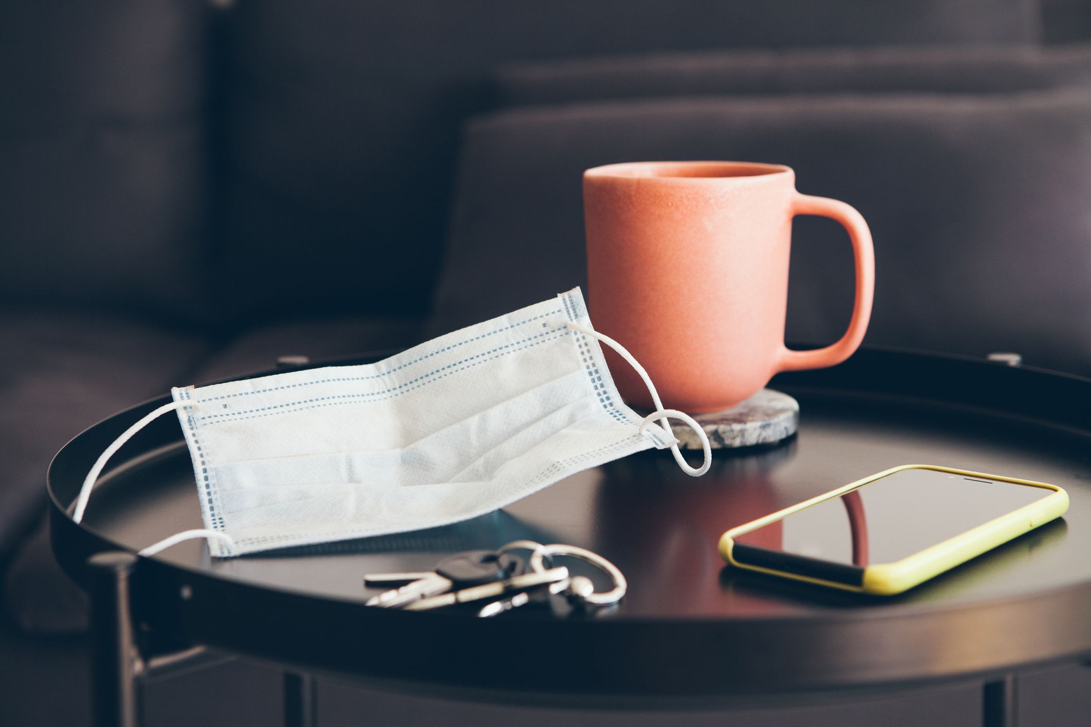 Self distancing. Close-up of coffee table with cup of English tea and face mask. Selective focus. Lifestyle photo