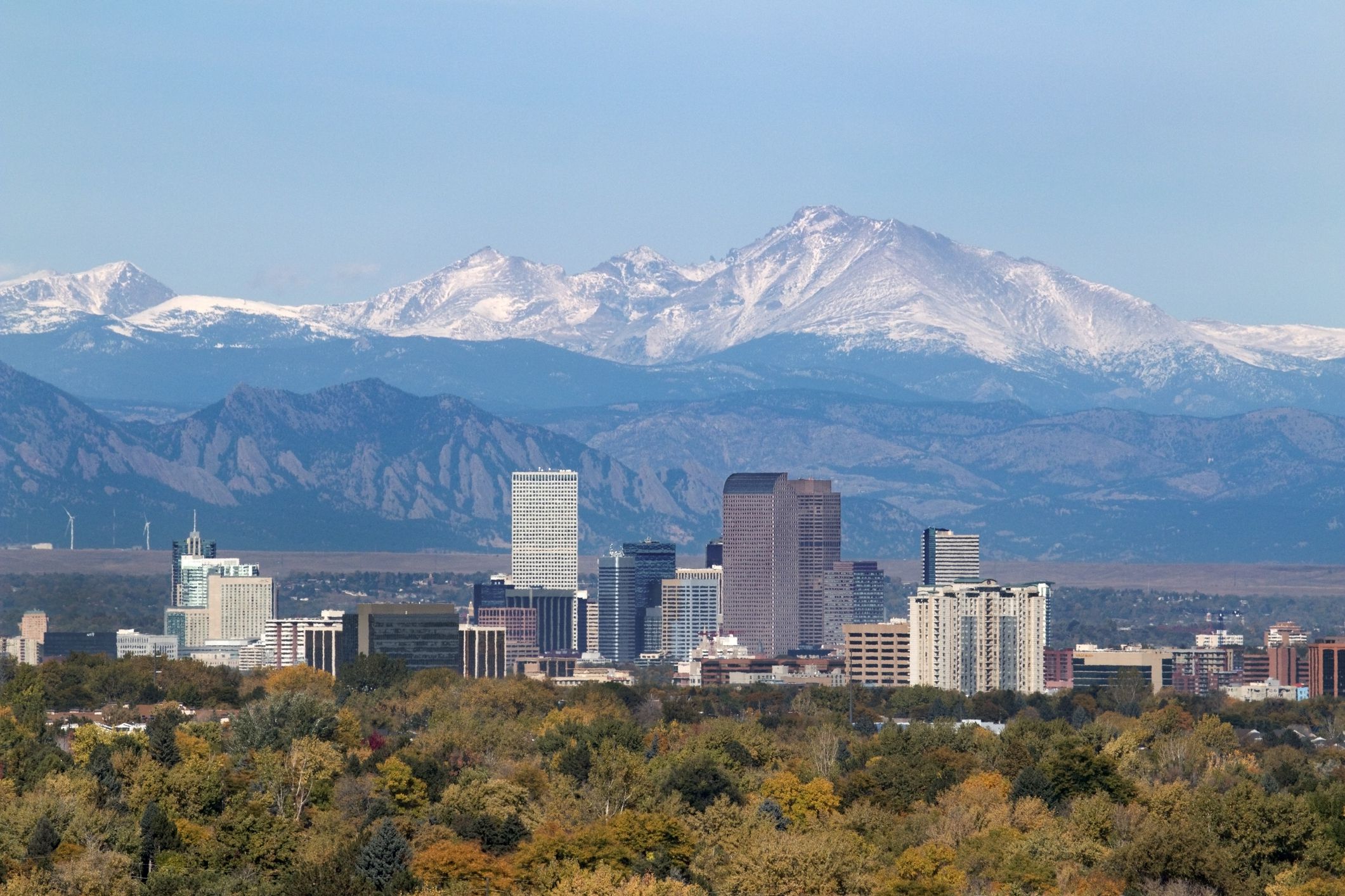With the snow covered Longs Peak part of the Rocky Mountains and the iconic flatirons of Boulder in the background, Downtown Denver skyscrapers including the iconic