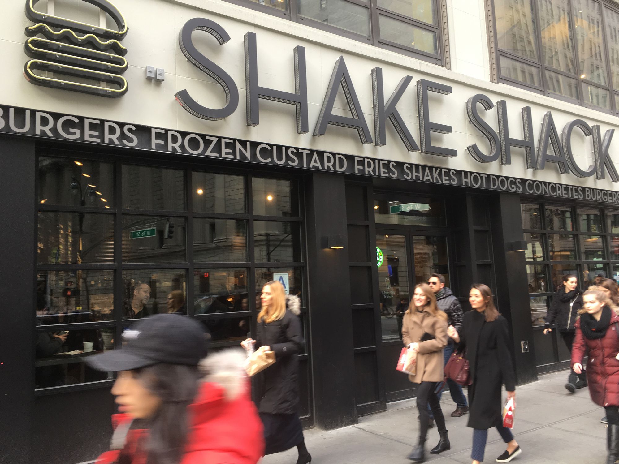 1 February 2017 - New York City: People passing a Shake Shack in Midtown Manhattan on a sunny afternoon during the lunch hour. Cold winter day in New York.