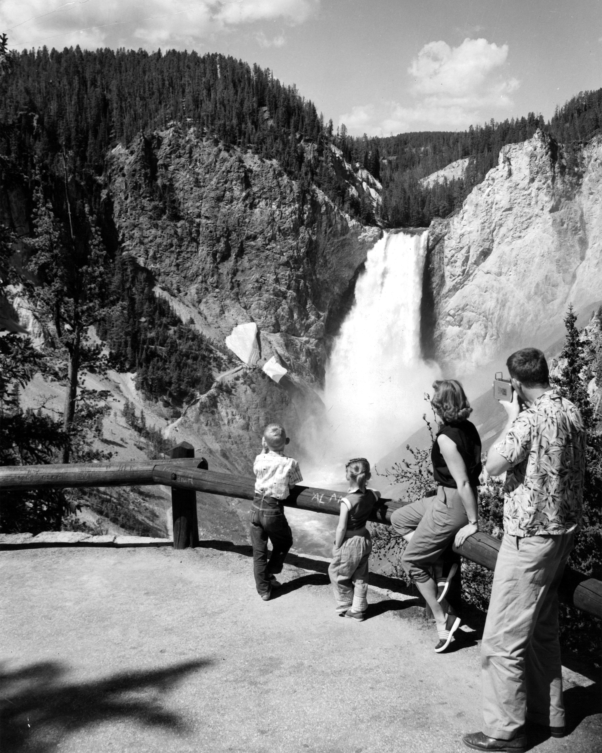 Tower Falls at Yellowstone, two small children and two adults stand watching the spectacular water fall