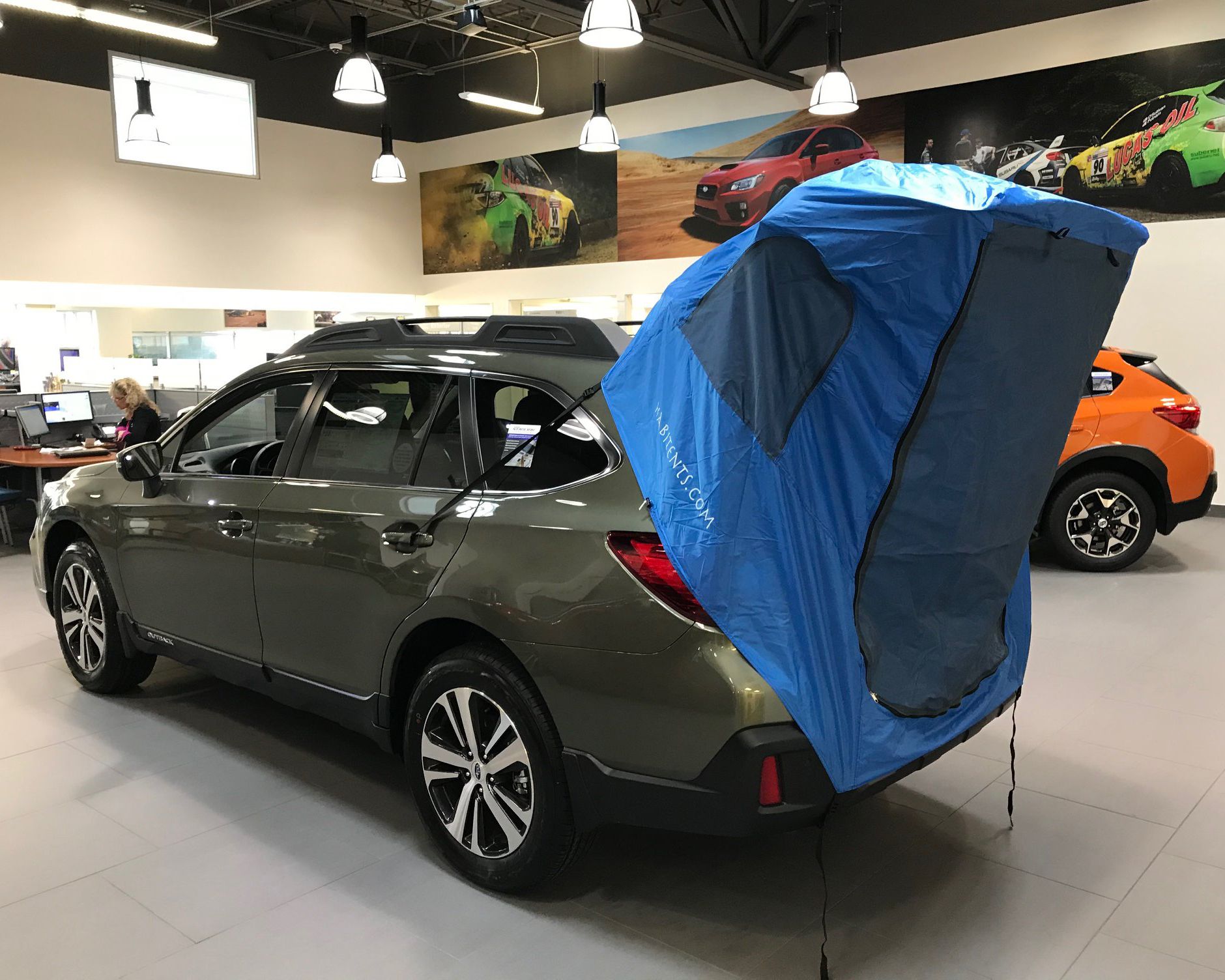 Habitents tent on a dark green wagon in a showroom.