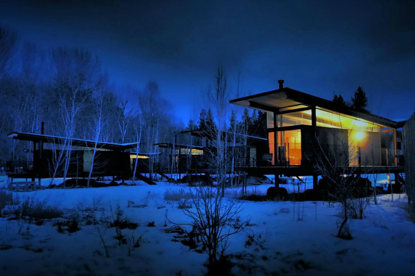 Modern cabins at night in snow.