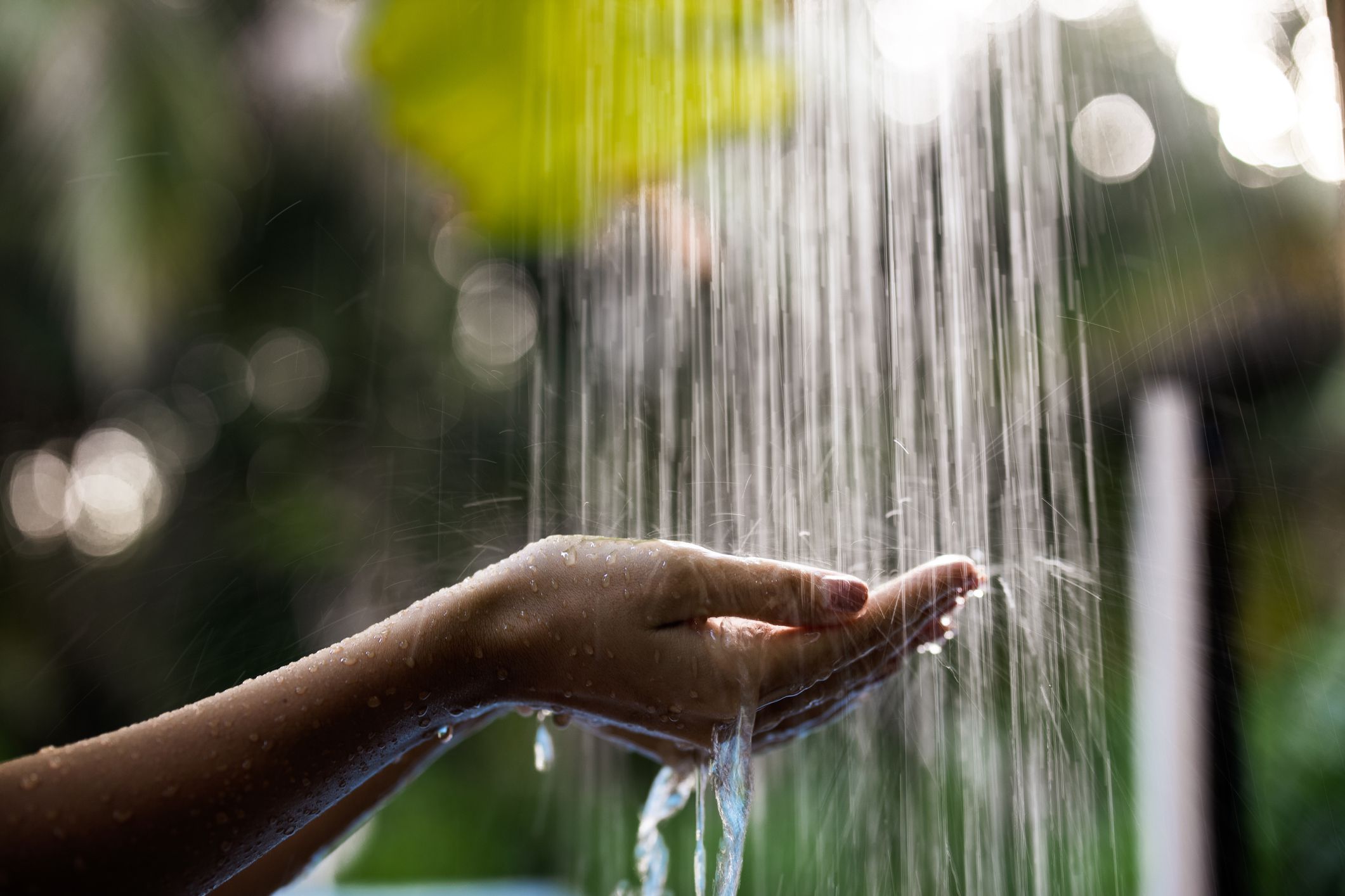 Close up of unrecognizable woman holding her hands under the shower during summer day in nature.