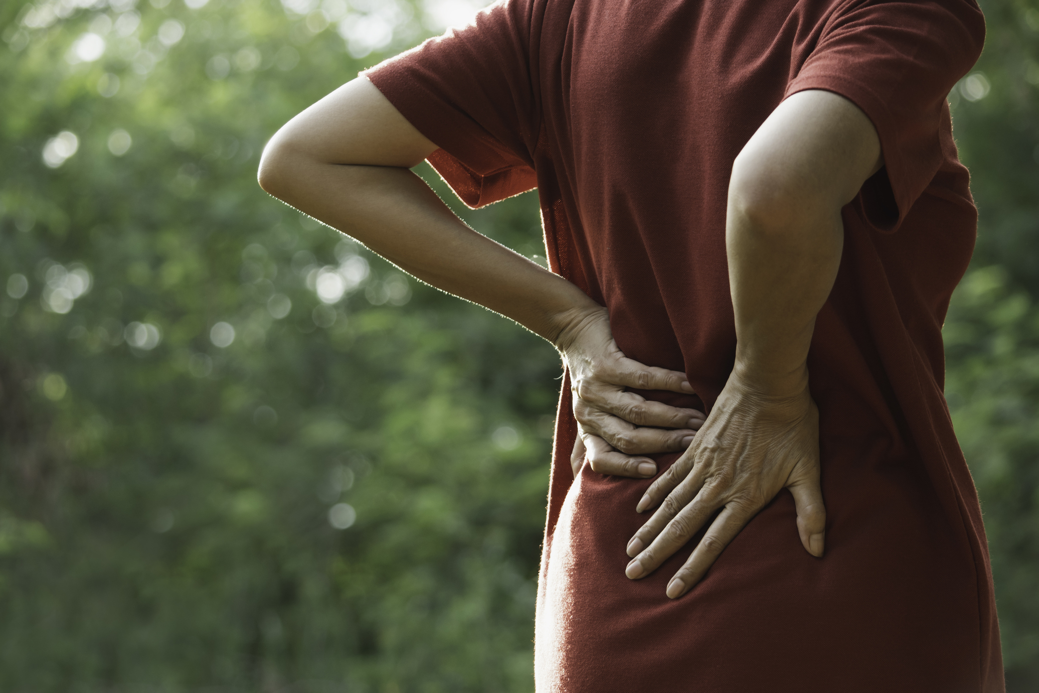 Closeup hands of woman touching her back pain in healthy concept on nature background.