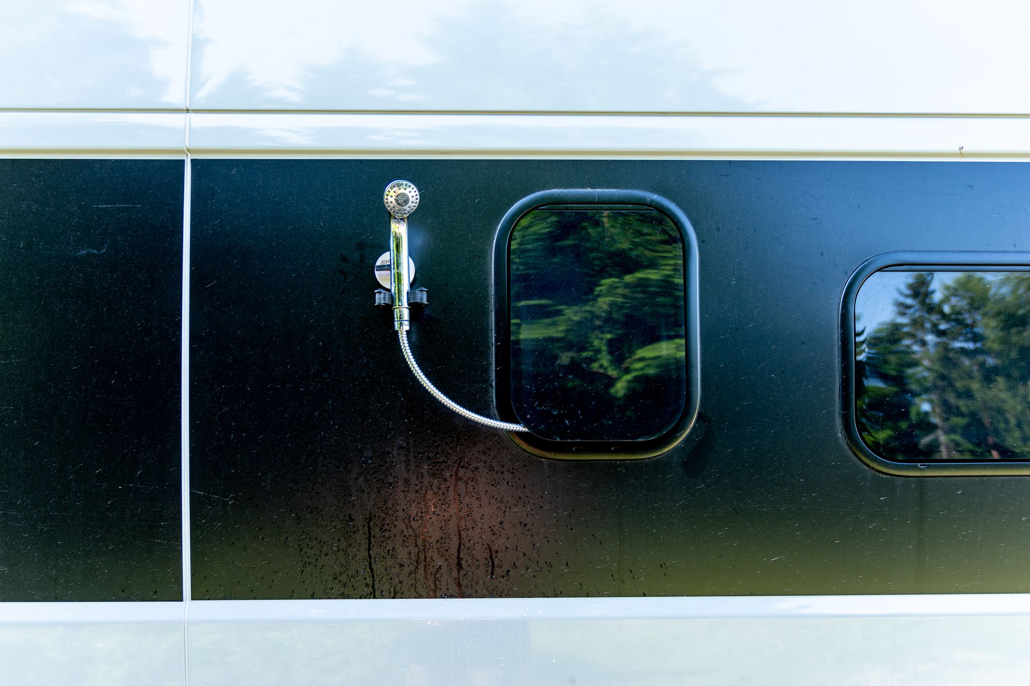 A close up view of an outdoor shower mounted with a suction cup on the side of a camper van