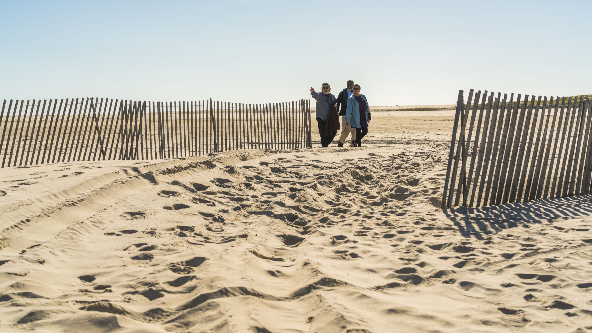 The group of senior friends walking on the Jones Beach, Long Island, USA