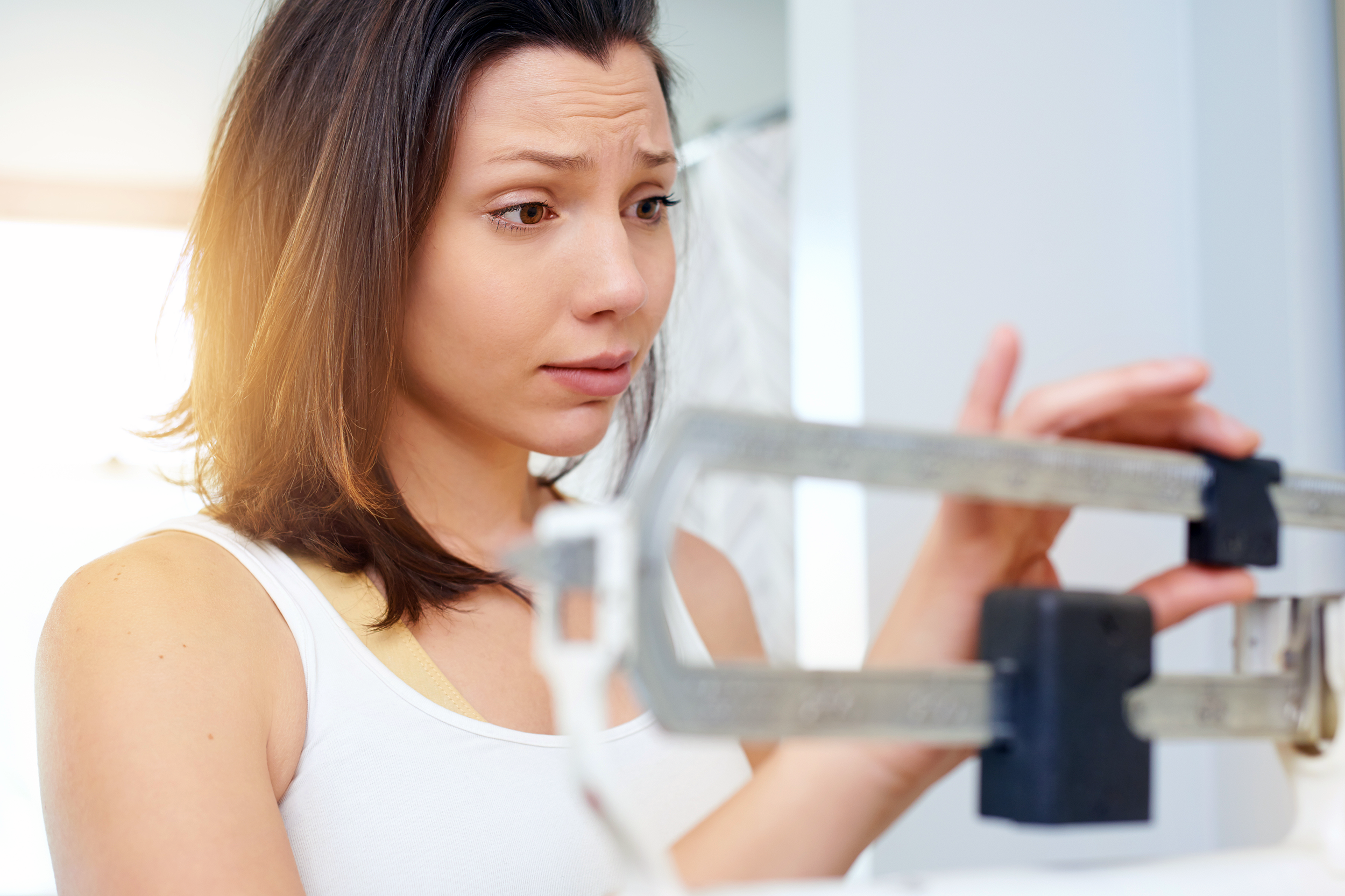 Concerned woman weighing herself on scale