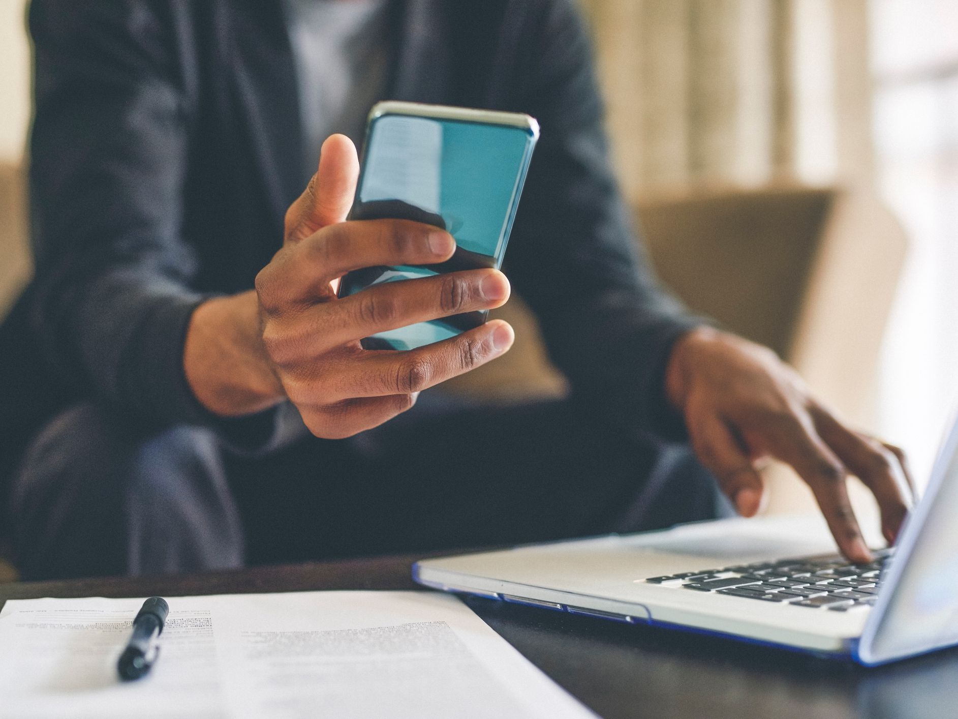 Cropped shot of an unrecognizable man using a smartphone and a laptop while working from home