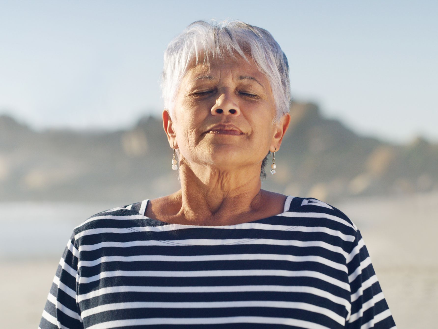 Cropped shot of an attractive senior woman taking a deep breath while standing alone on the beach