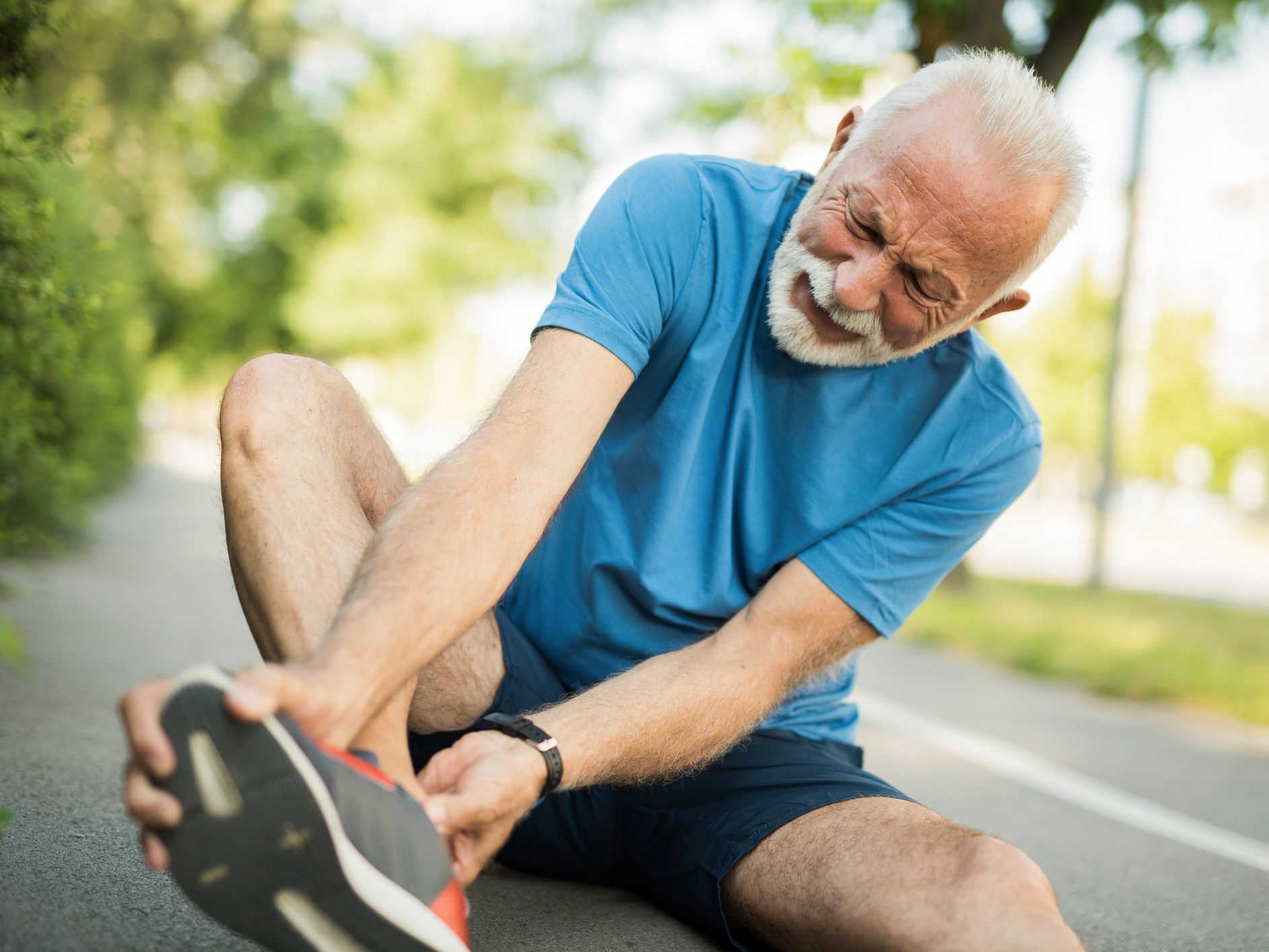 Sporty senior man having leg injury outdoors.