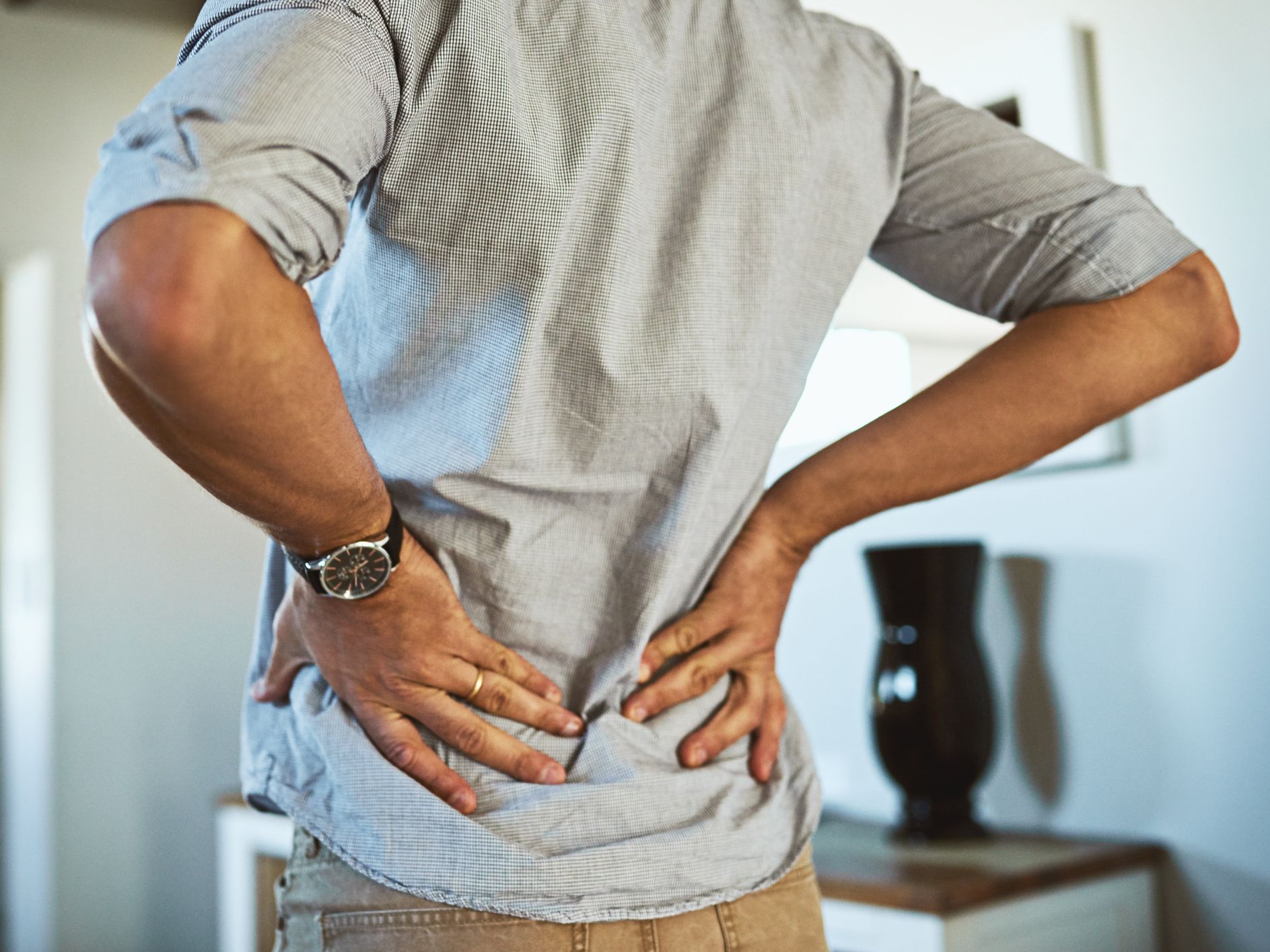 Rearview shot of an unrecognizable man holding his back in discomfort due to pain inside at home