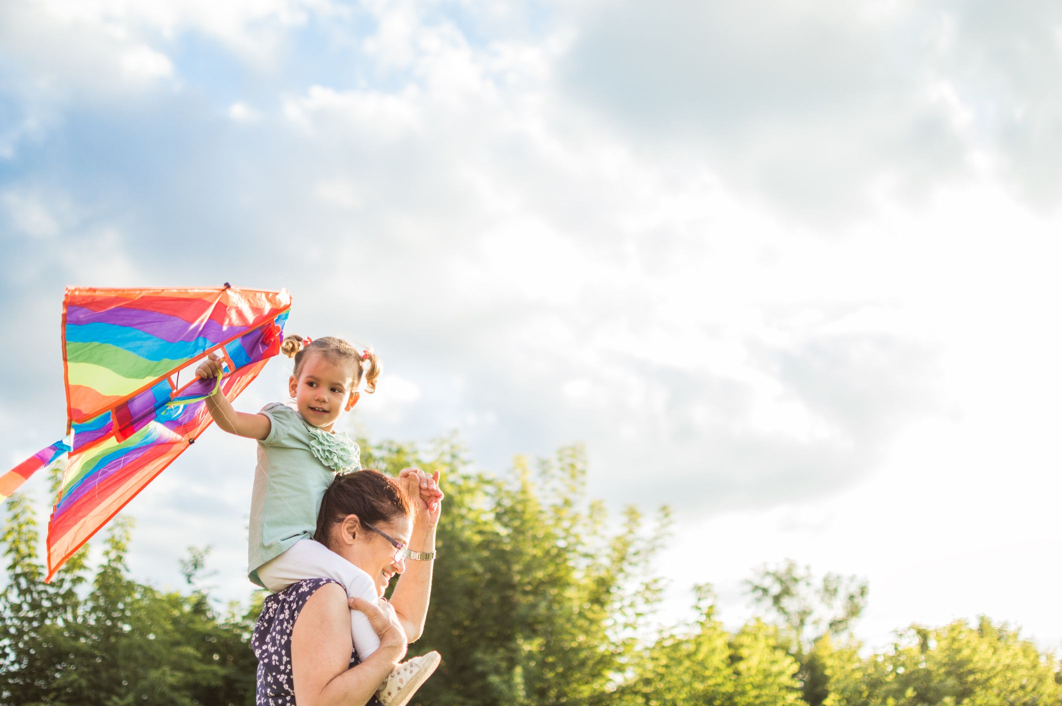 Grandmother and granddaughter having fun, playing with kite together.