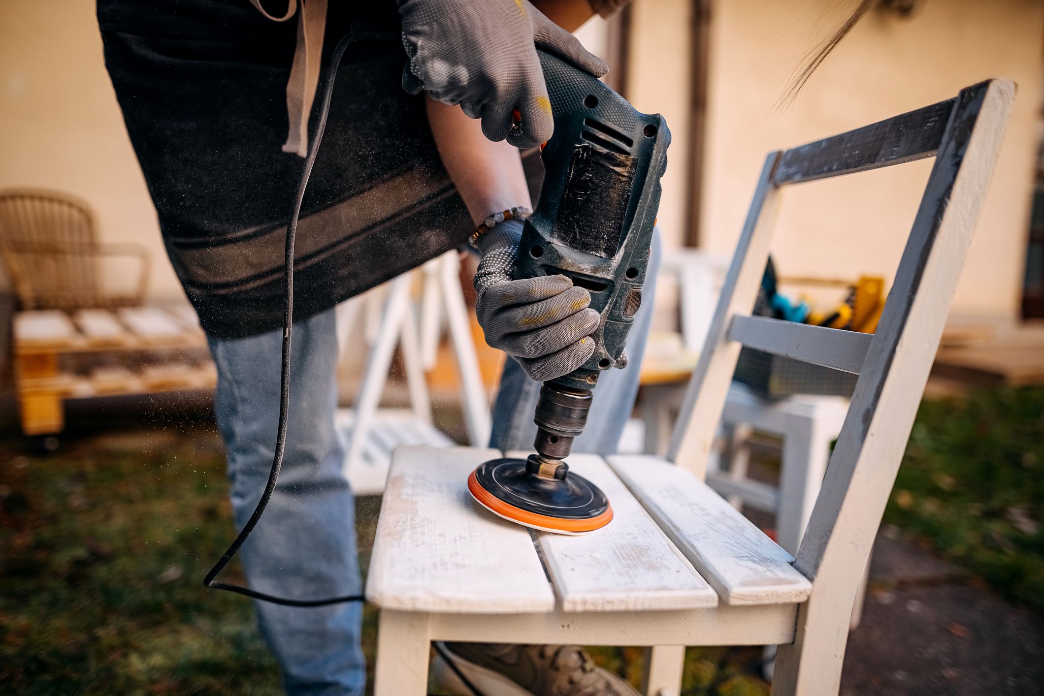 Young women sanding furniture in backyard, preparing for painting