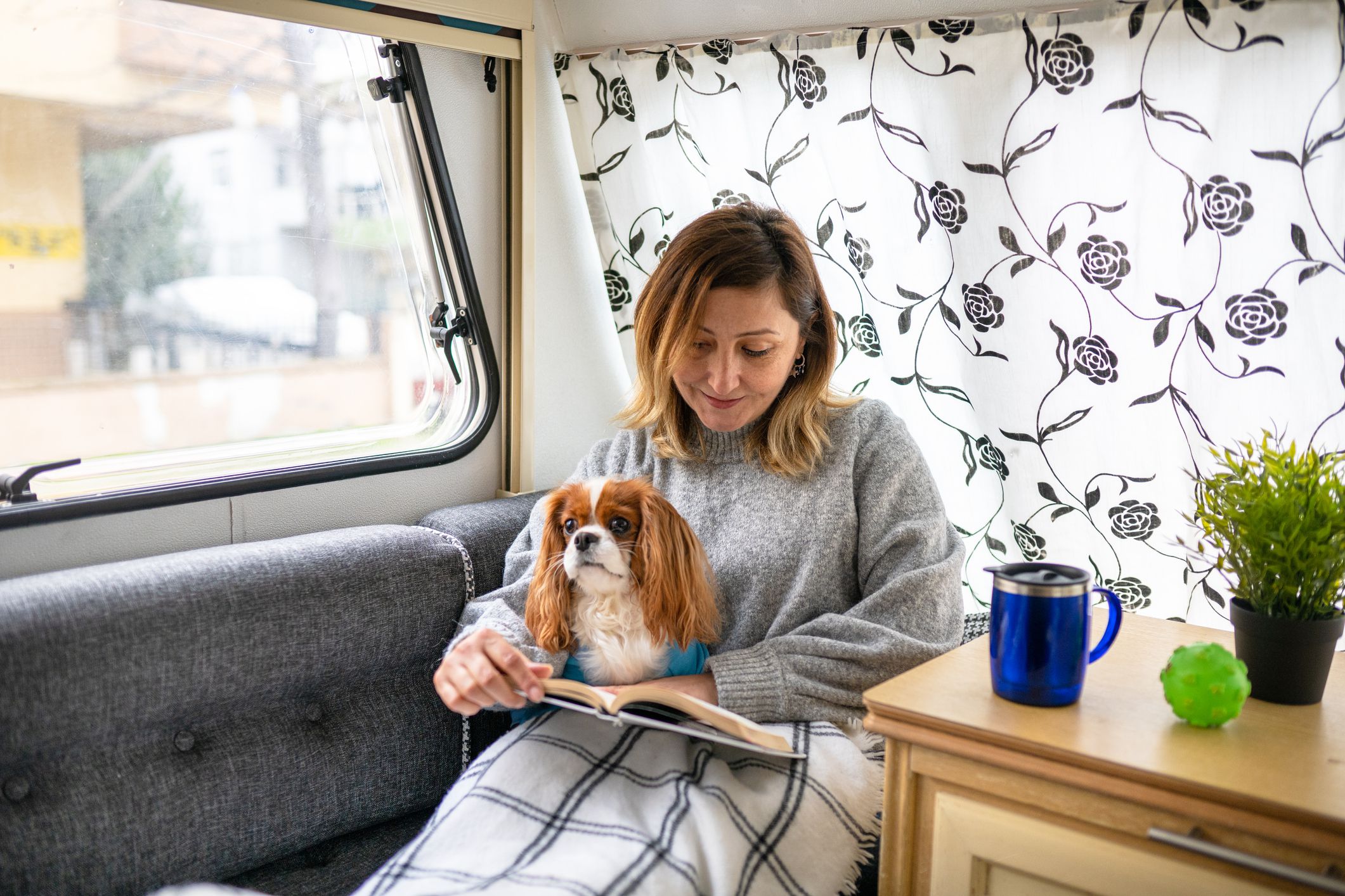 adult woman reading a book in the trailer with her dog