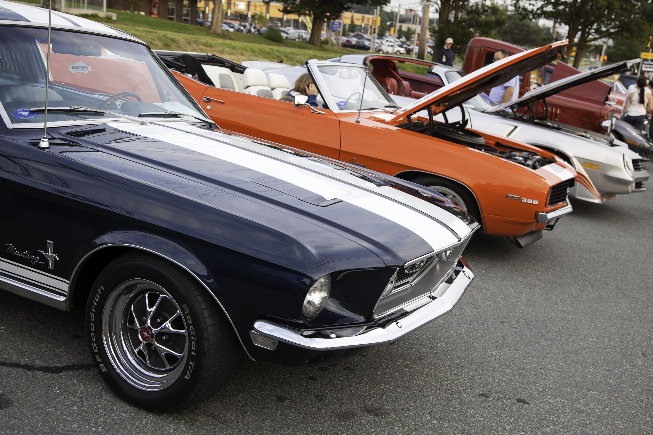 Dartmouth, Nova Scotia, Canada - August 22, 2013: Many classic cars are parked in a row during a public car gathering. Cars include a Ford Mustang, a two Chevrolet Camaros. In the background people are visible admiring the vehicles.