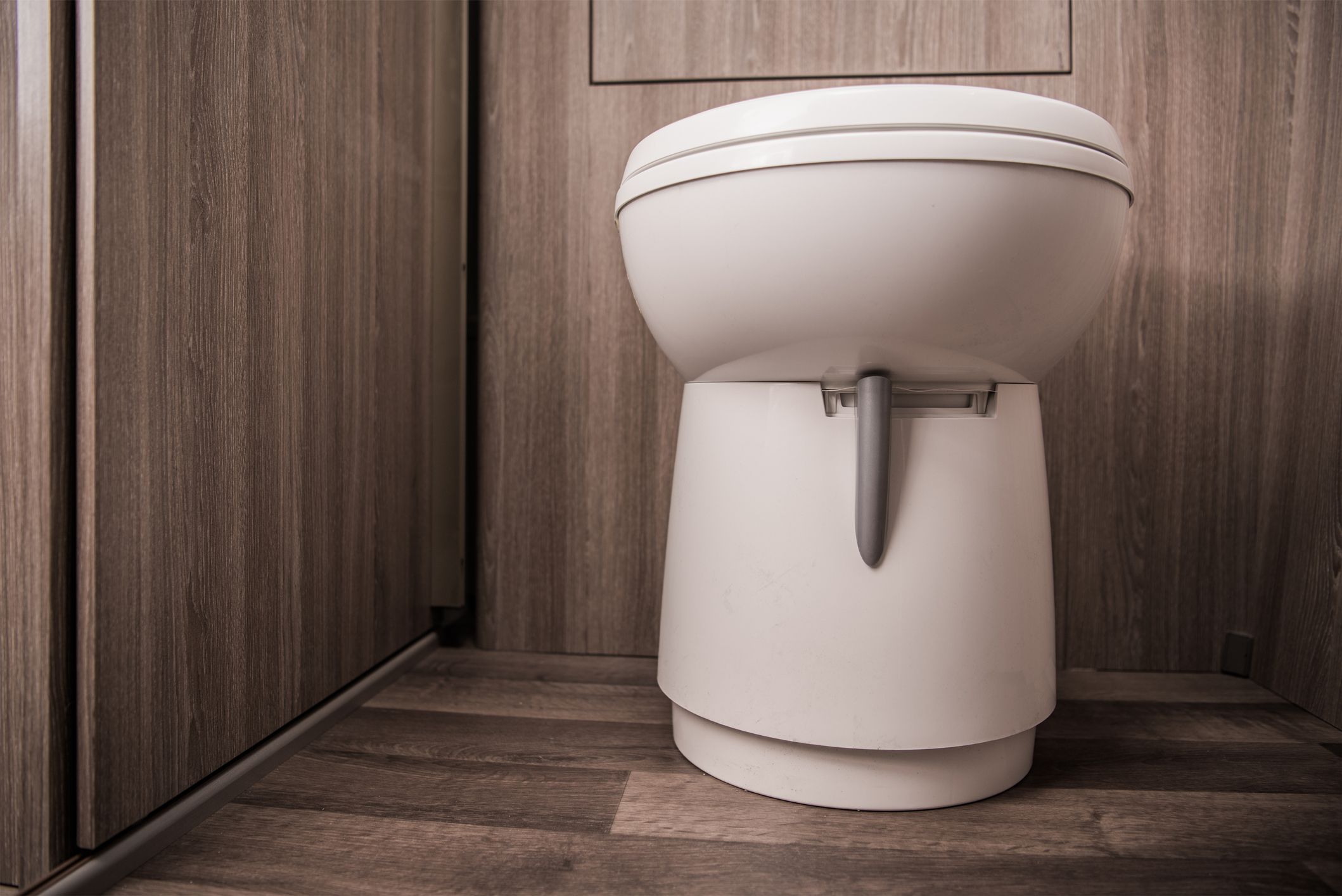 Close Up Of White Toilet In Tan Small Area Of Recreational Vehicle Restroom Cabin.