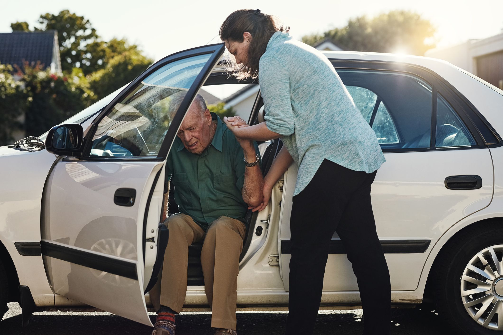 Shot of a woman helping her senior father out the car