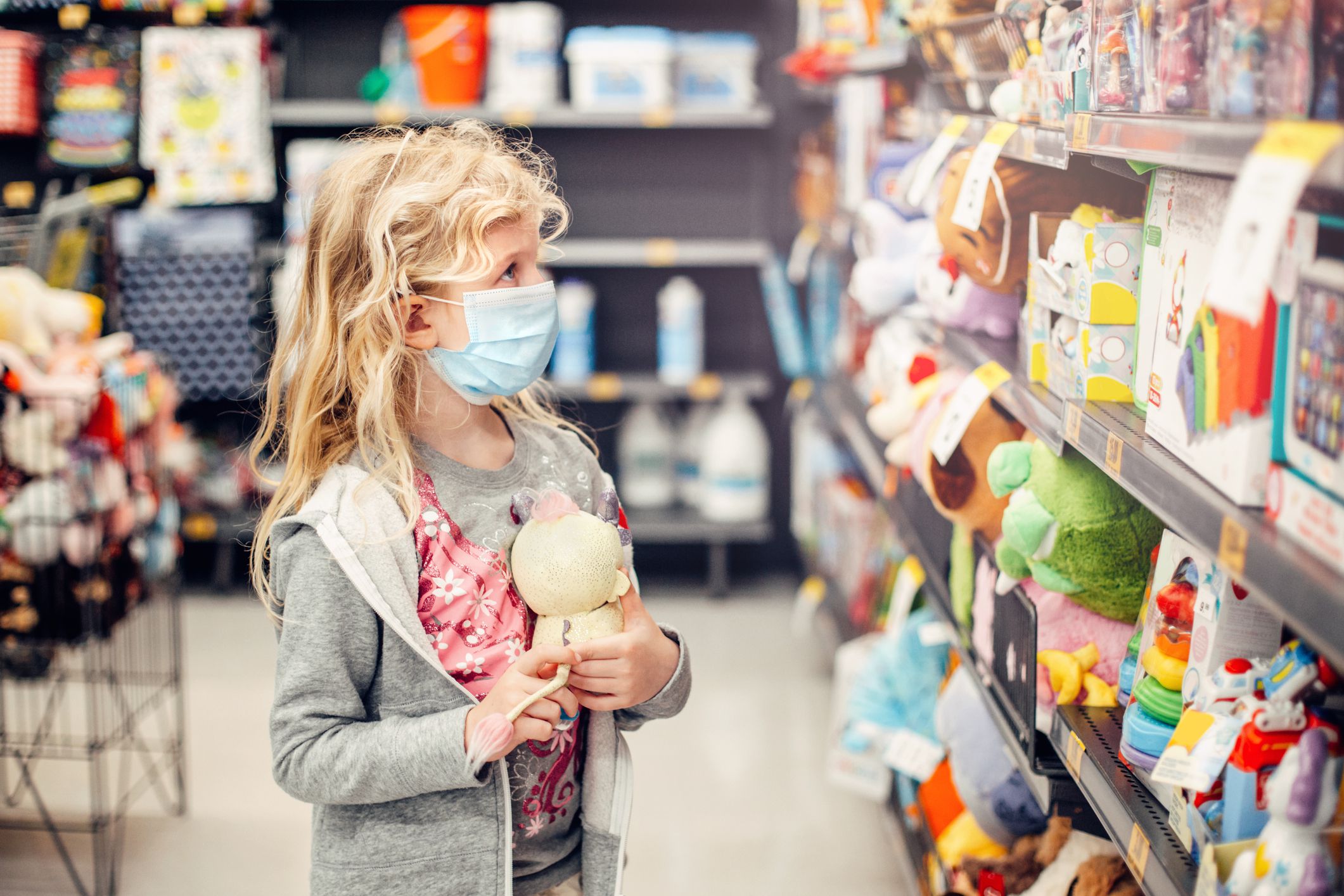 girl in sanitary face mask shopping at toy store
