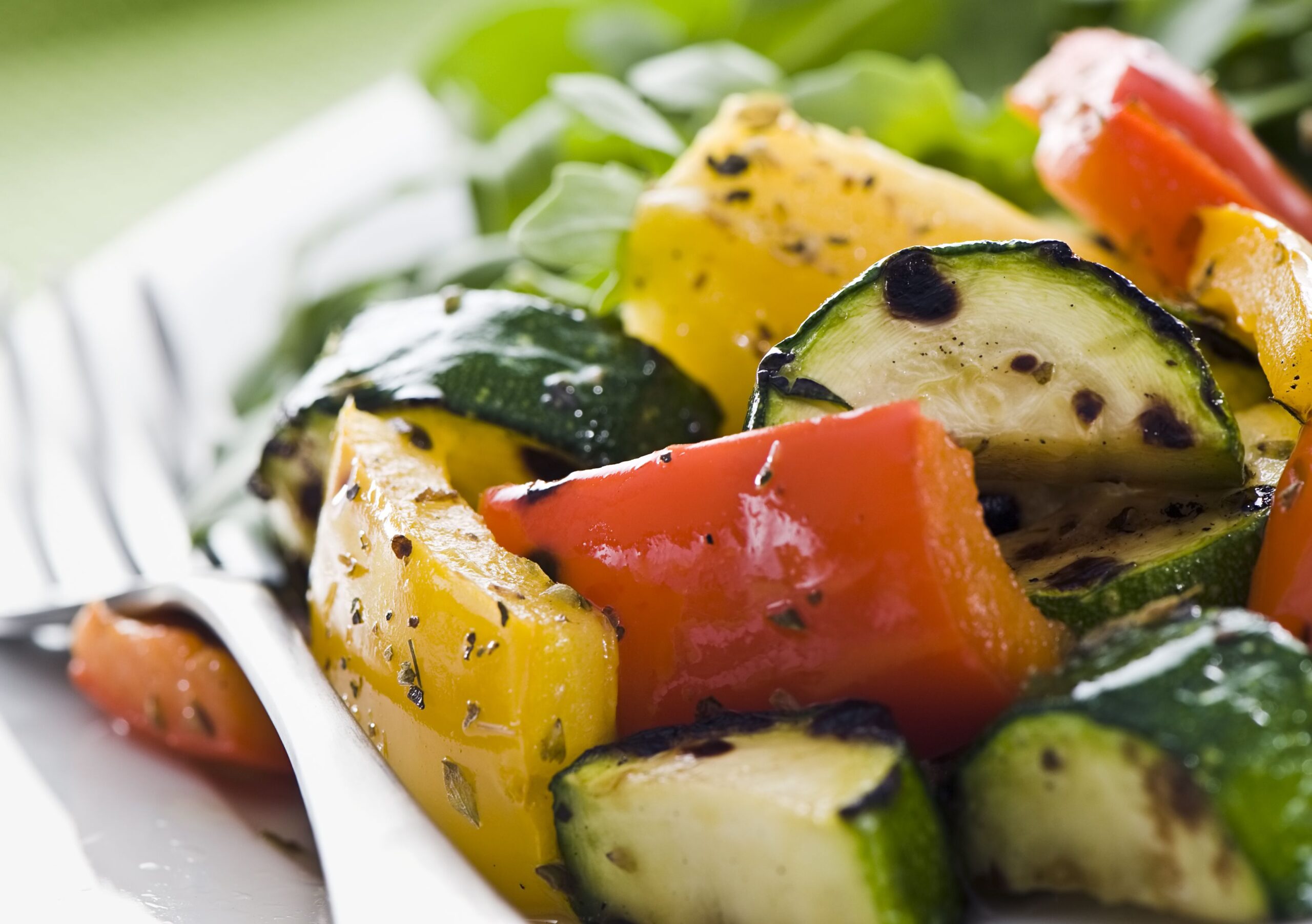 Plate of grilled vegetables with arugula salad on a green background
