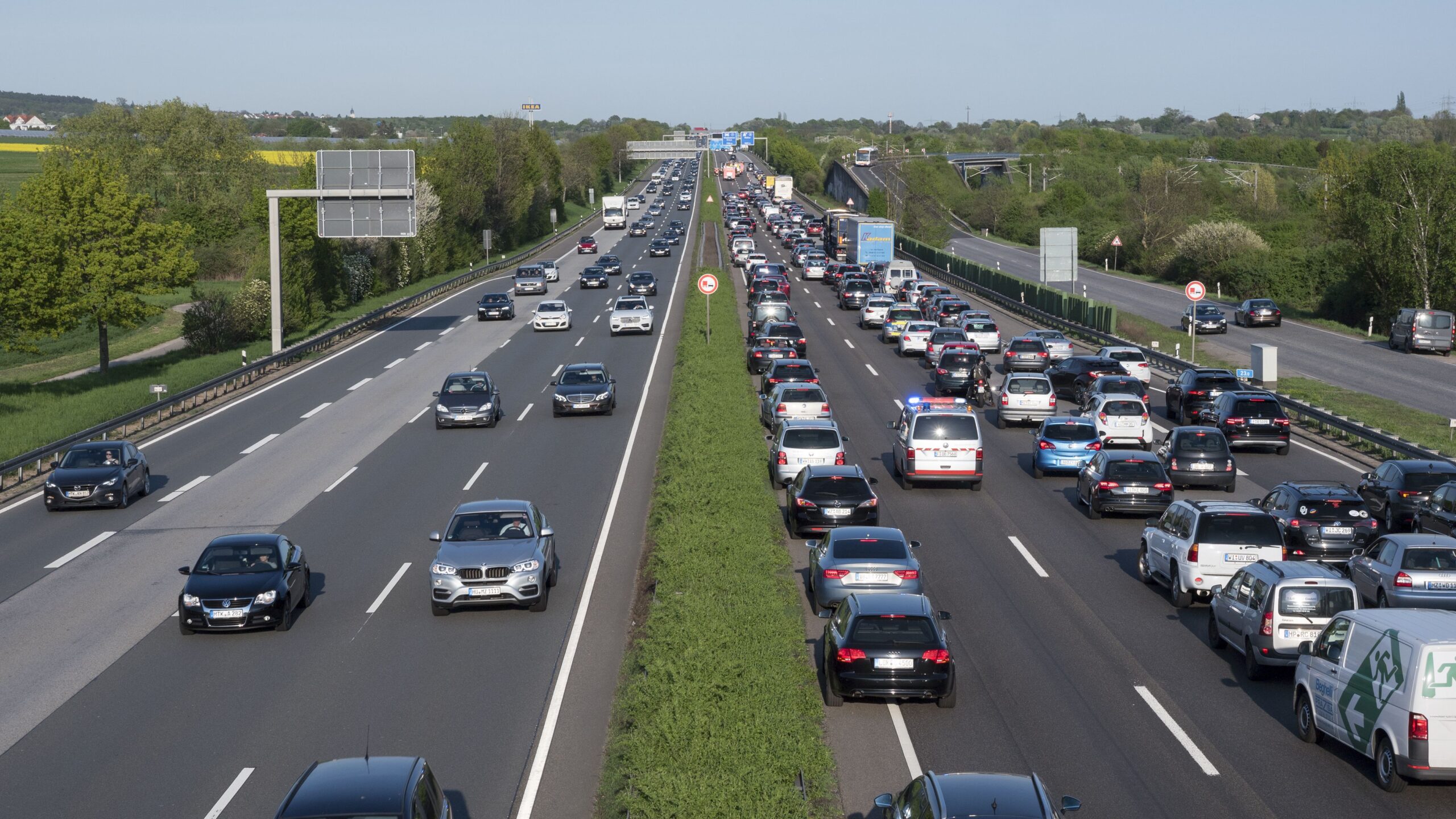 Wallau, Germany - April 20, 2018: Traffic jam on German highway A66 between Wiesbaden-Nordenstadt and Wallau caused by an accident during rush-hour. Road users forming an emergency corridor for emergency vehicles. High-angle view from a bridge.