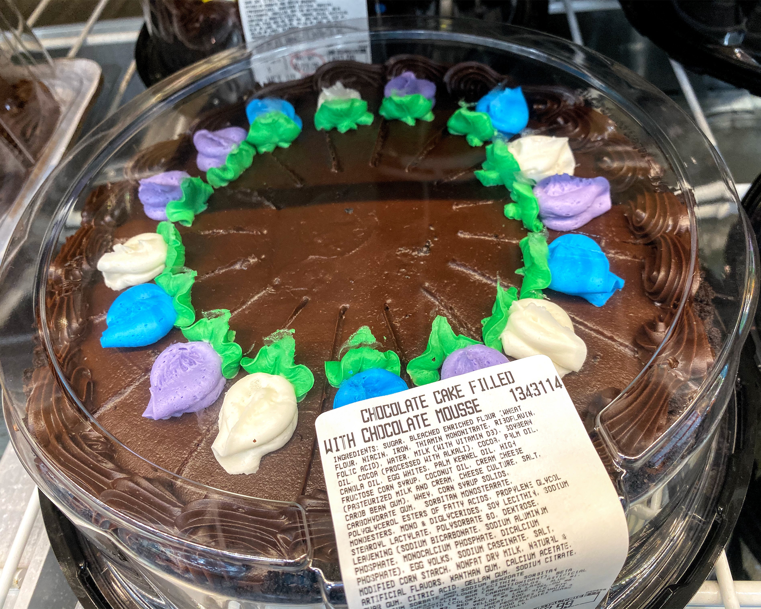 Closeup of Kirkland Chocolate Cake Filled With Chocolate Mousse at a Costco in an outside refrigerator, surrounded by other cakes