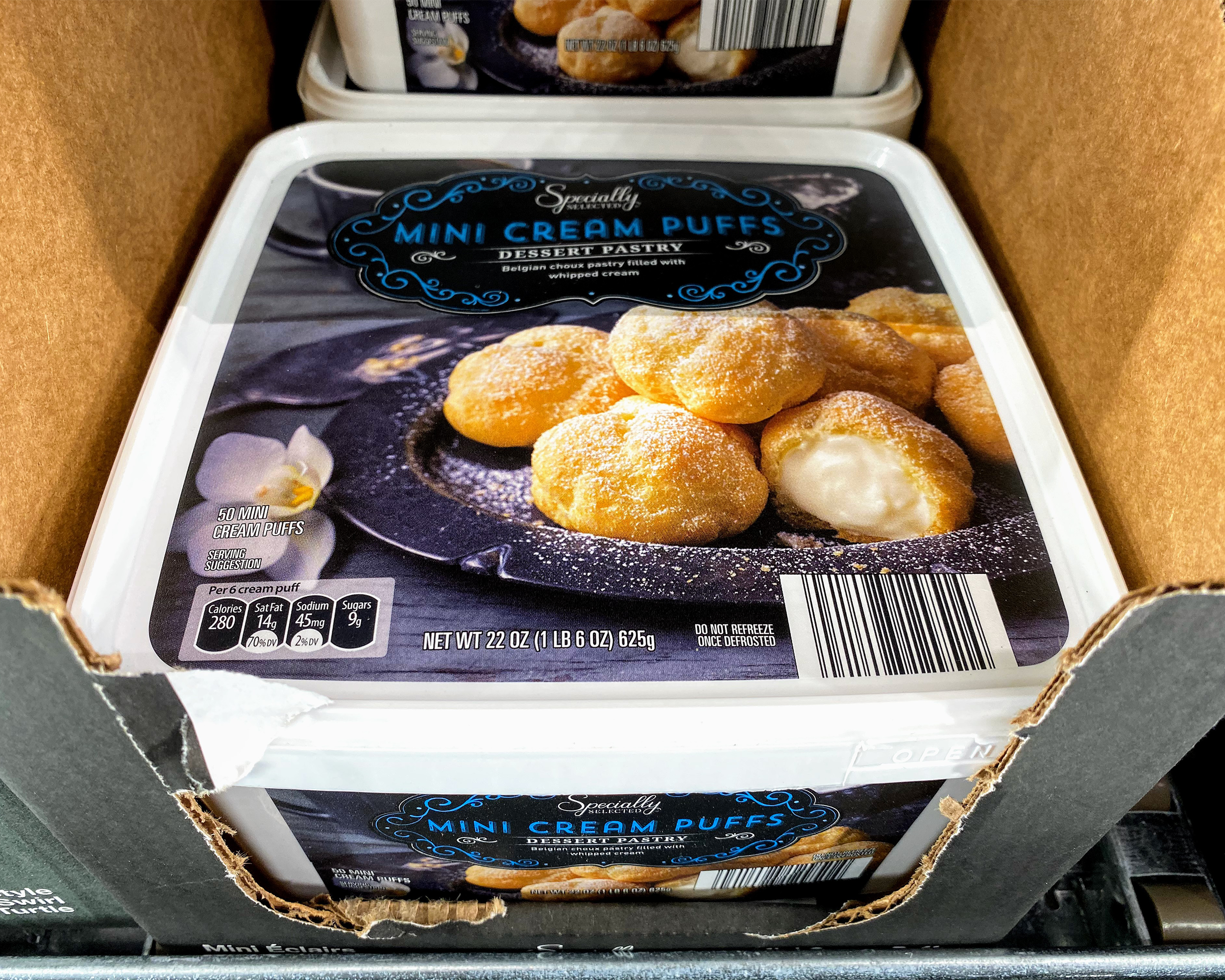 Closeup of Belgian Mini Cream Puffs at a Costco, two rows in a box in a refrigerator