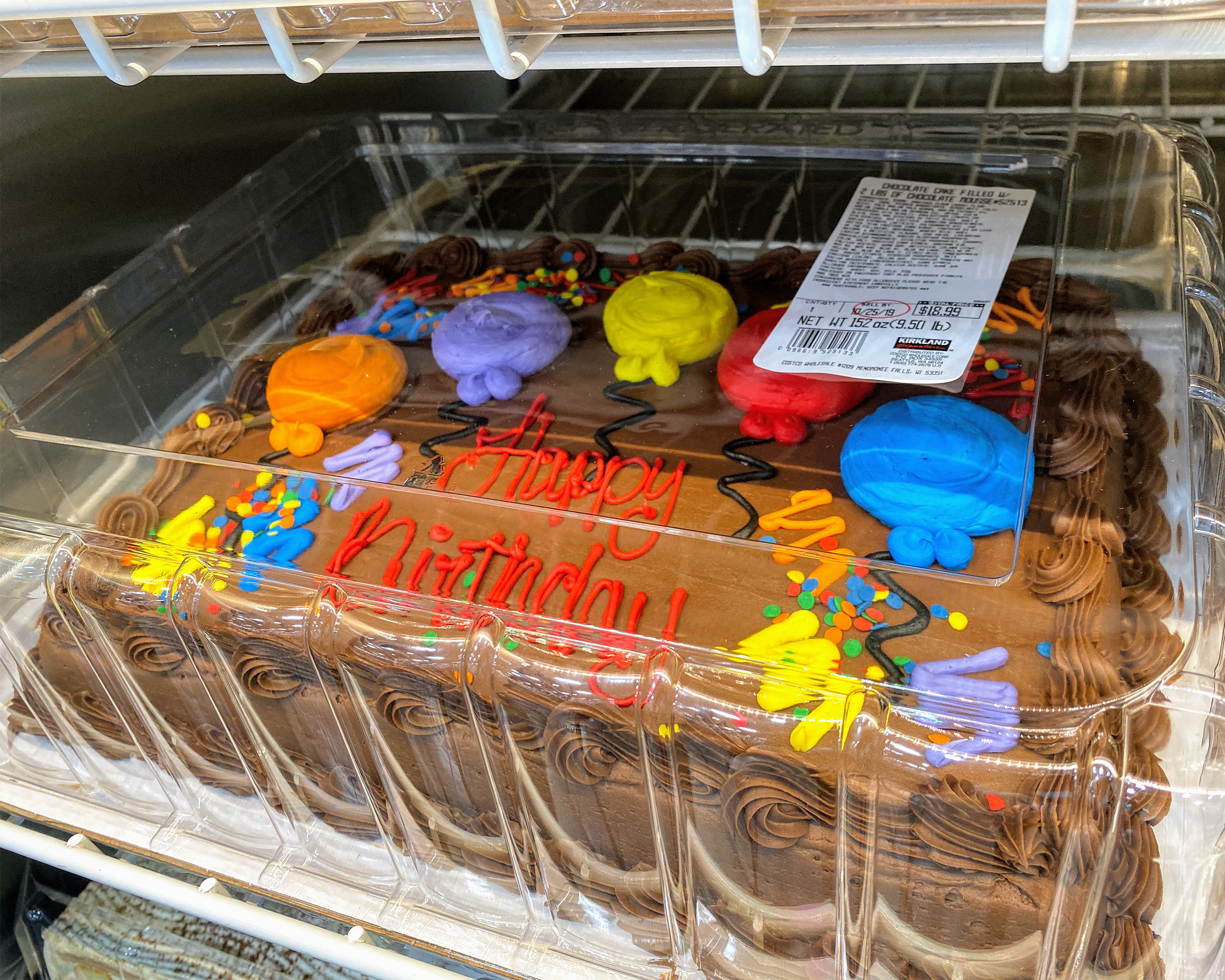 Closeup of Kirkland Chocolate Sheet Cake with Happy Birthday balloons Icing Decoration at a Costco in a refrigerator, a row below and above
