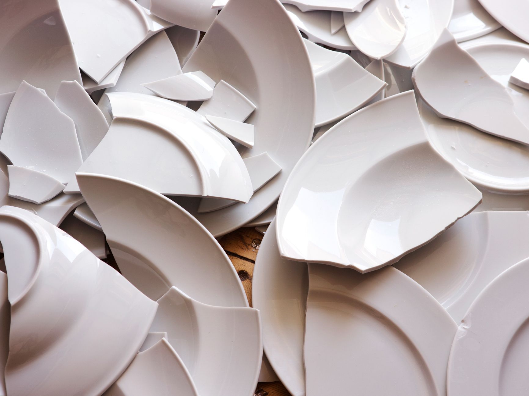 many white broken plates on a wooden floor