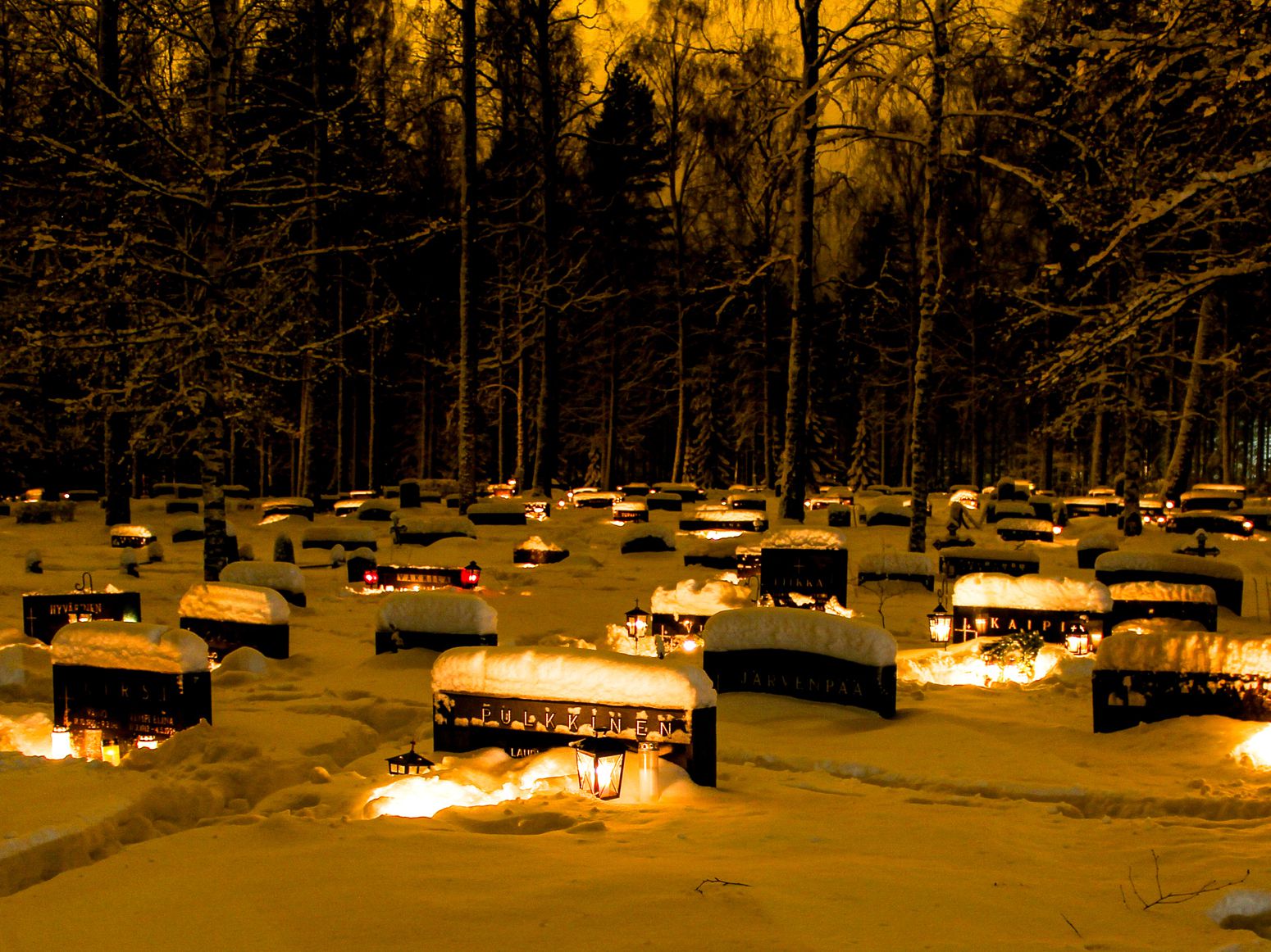 Candle lit snowy cemetery in Christmas time