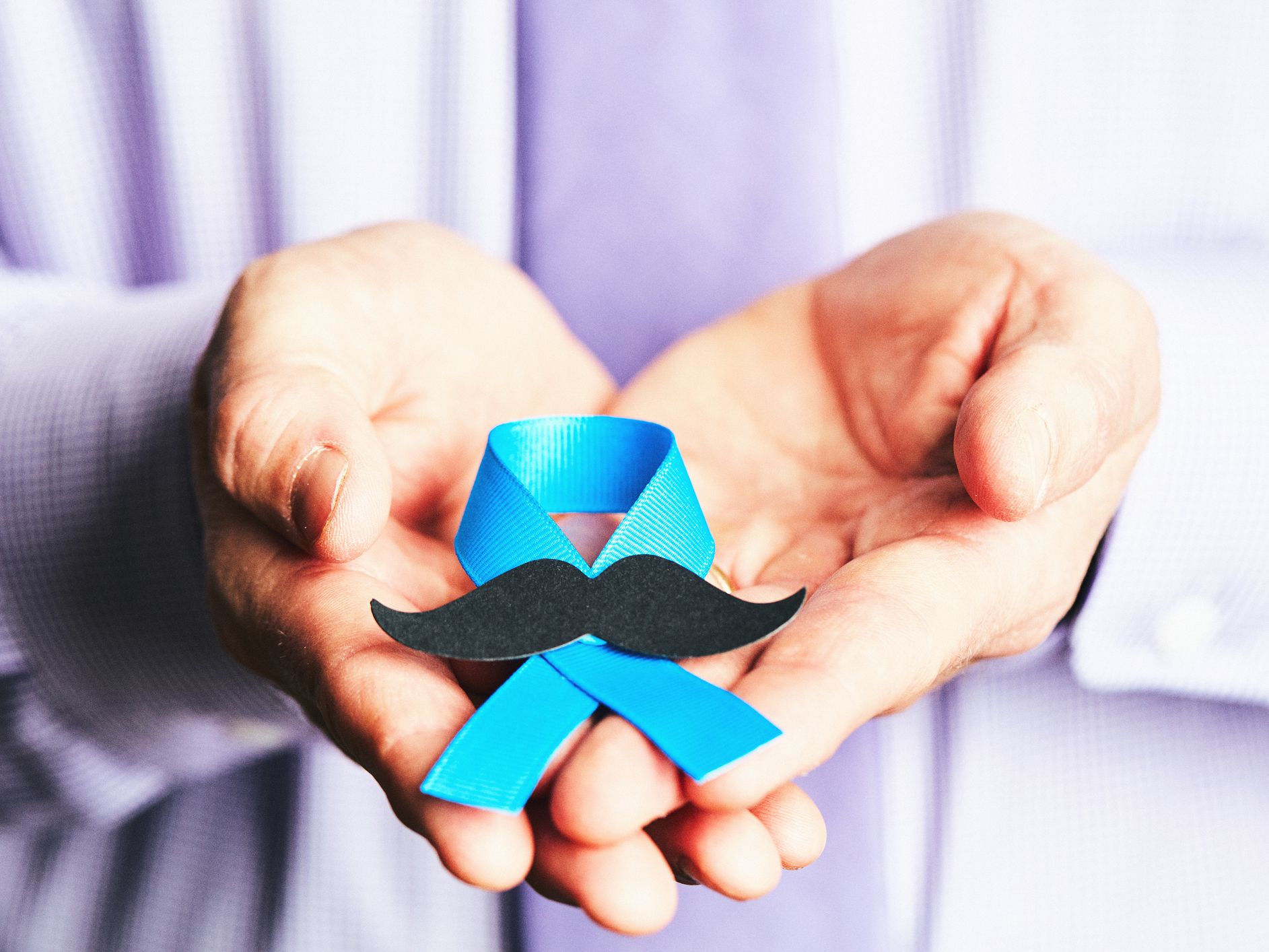 Male hands holding prostate cancer awareness ribbon with mustache