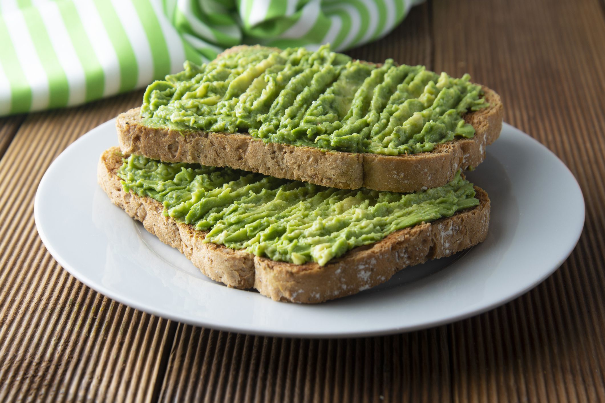 Healthy avocado sandwich, toast bread. Mushed avocado paste, on wooden background