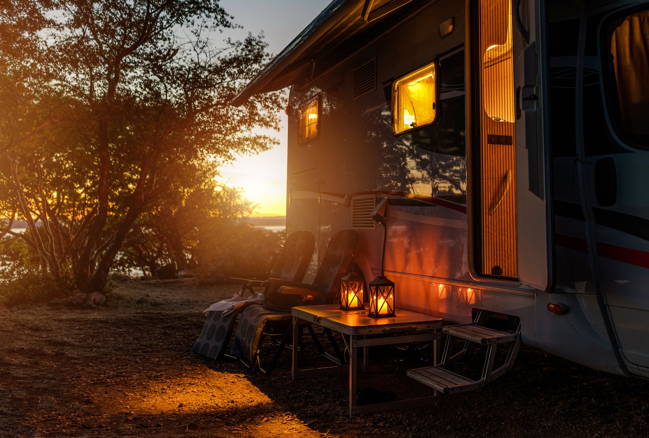 Road Trip Adventures. Calm Warm Night on a Camping. Camper Van, Outdoor Chairs and Romantic Light From Lanterns. Vacation in Recreational Vehicle.