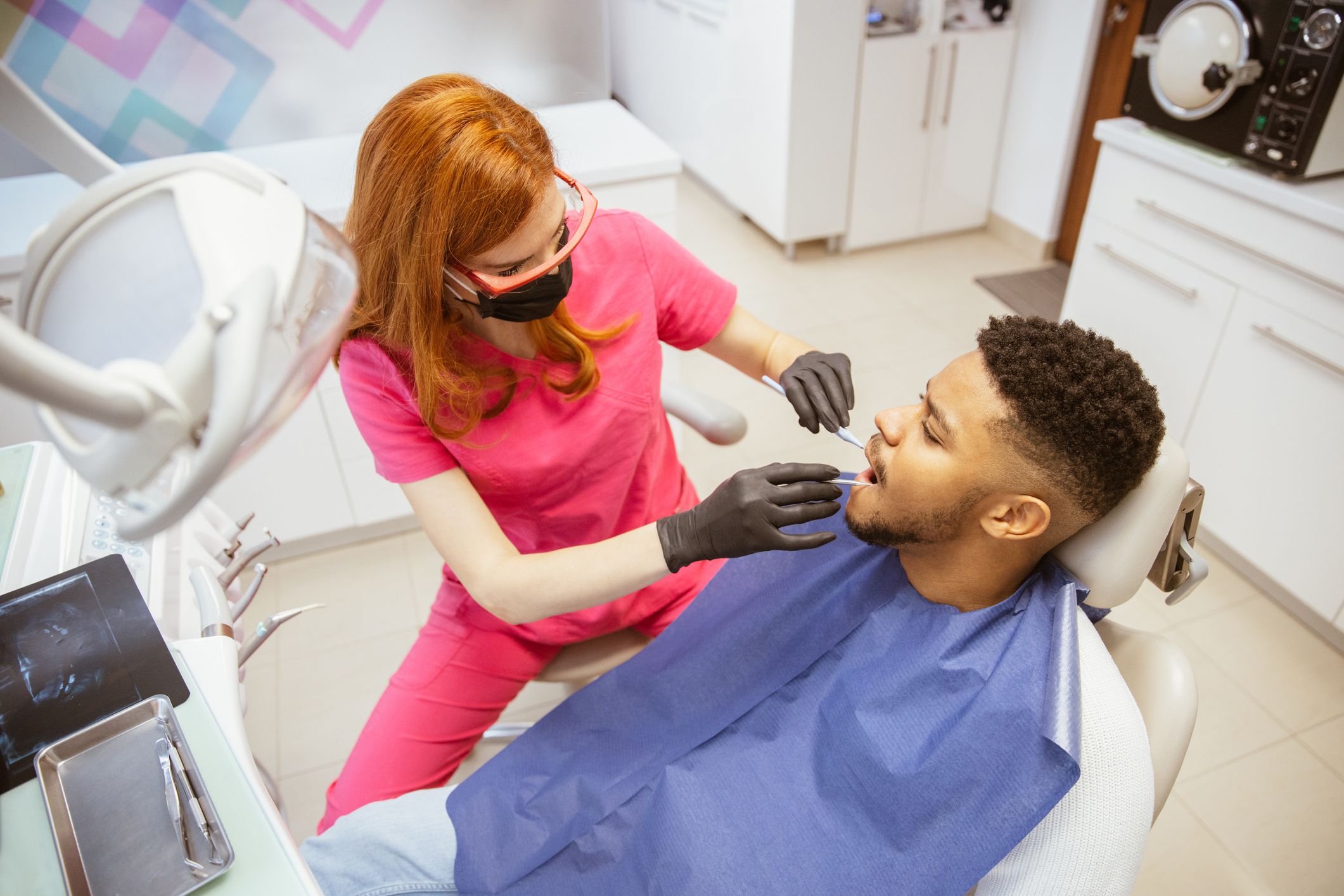 Young African-American man is sitting on a dental chair in a dental office. Examination and repair of teeth. Two people .