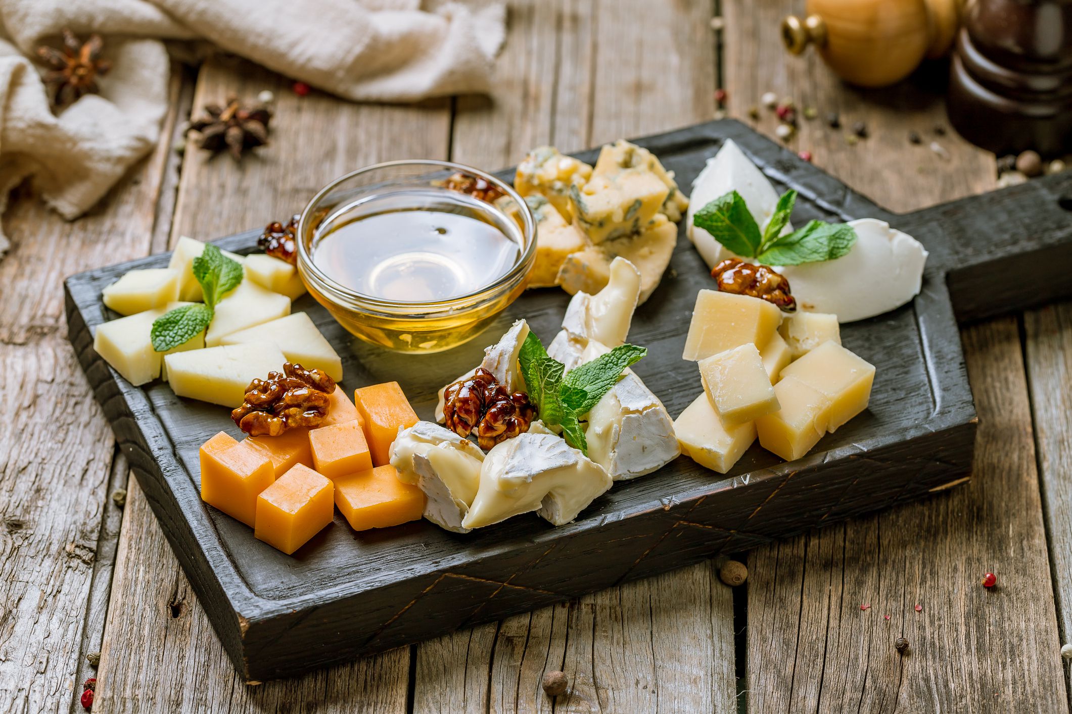 Cheese plate italian food with honey, mint and walnuts on beautiful wooden board on old wooden table