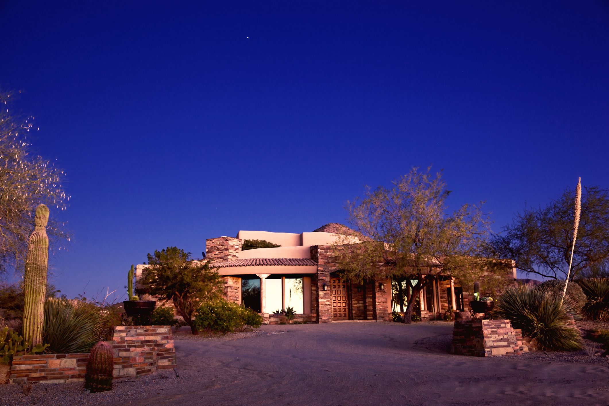 Luxury North Phoenix and Scottsdale, AZ modern stone and adobe home in a desert landscape setting on a clear sky at twilight, clear blue night sky
