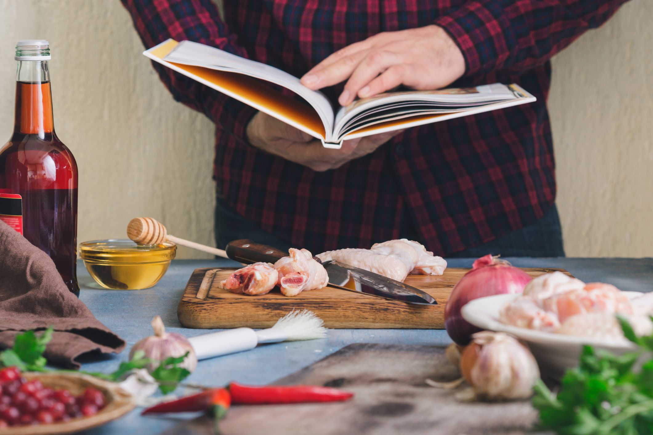 Man prepares chicken wings with cranberry sauce in a home kitchen