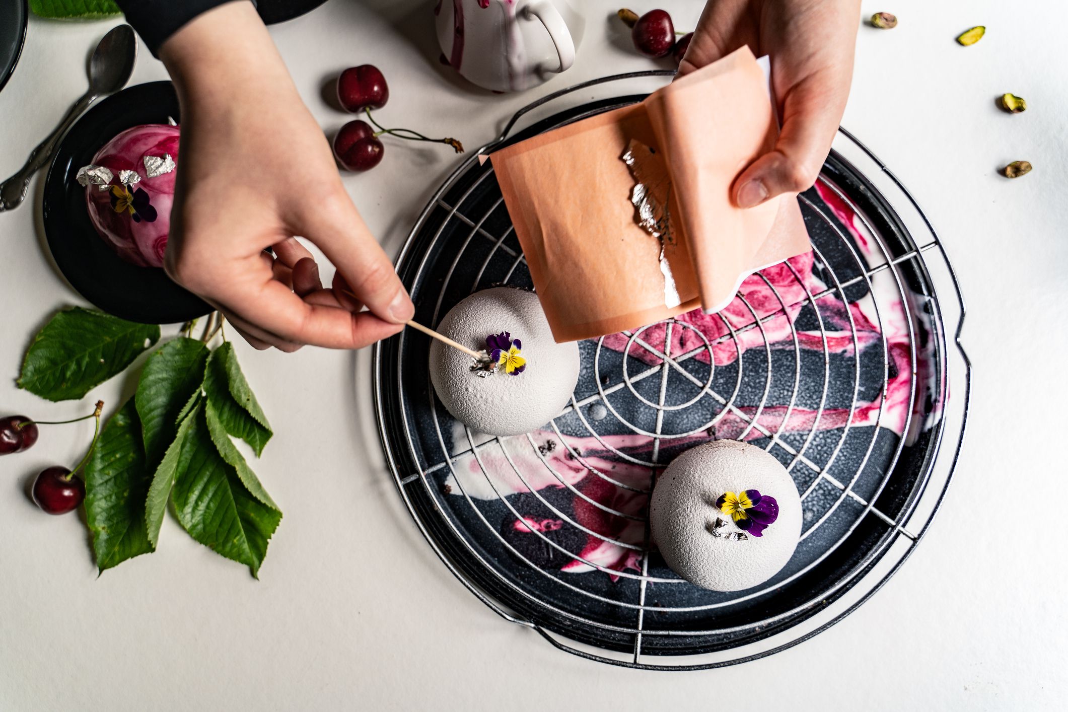 High Angle View of Woman Placing Edible Flowers on Homemade Desserts Resting on Rack