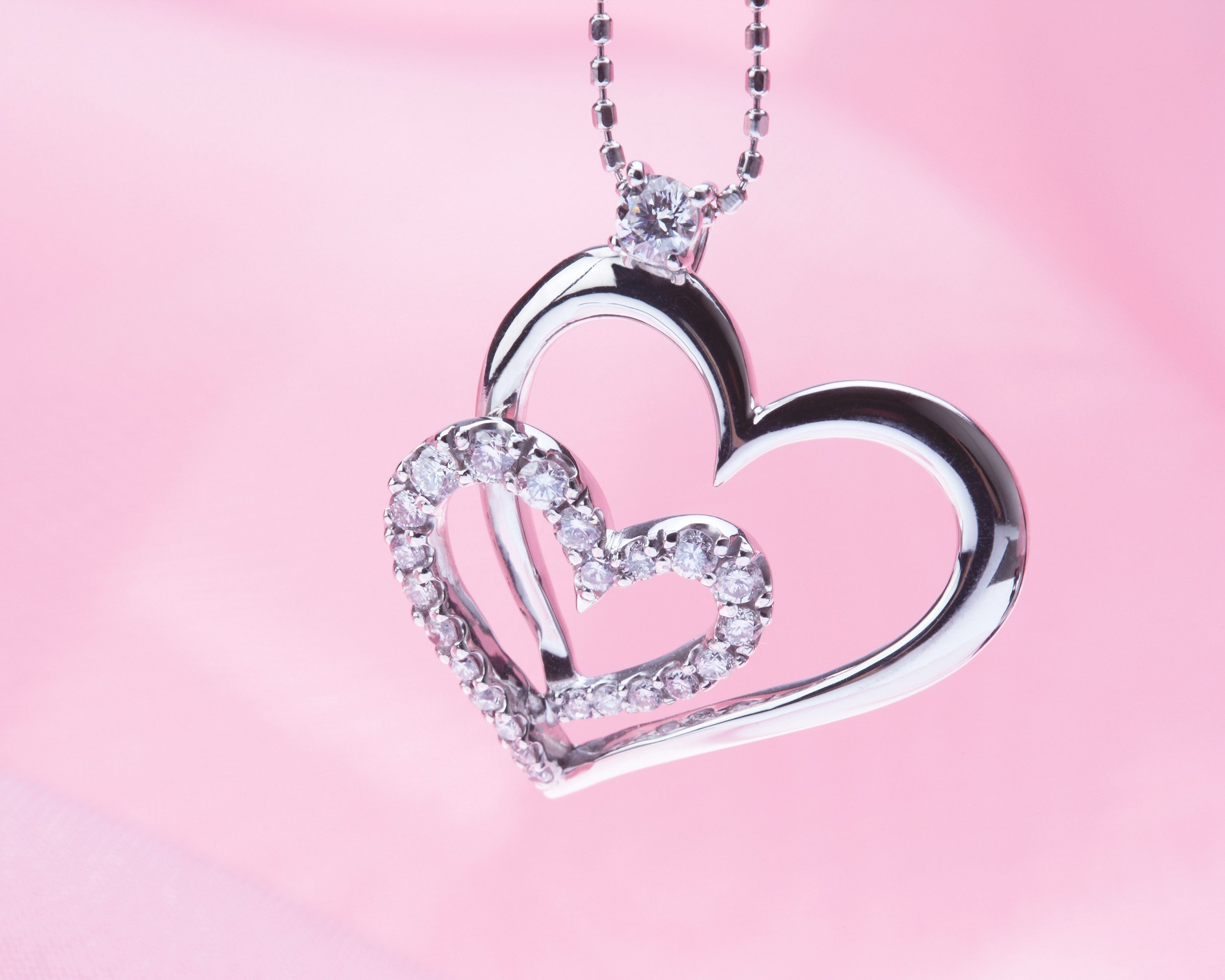 silver heart pendant against pink background