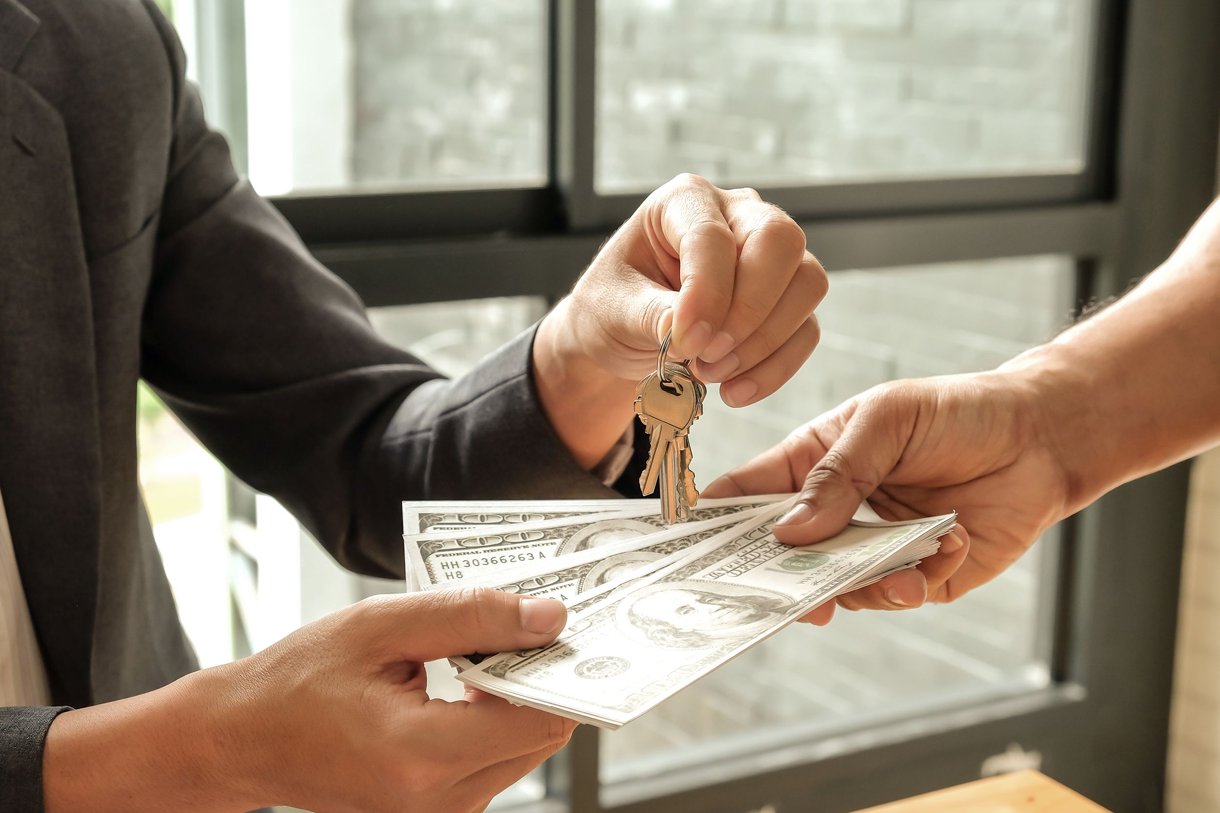 one hand giving $100s to landlord holding keys