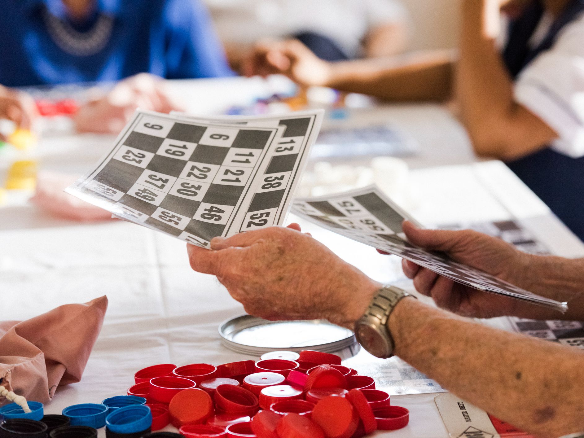 Close up senior mans hands passing out number cards for a game of bingo