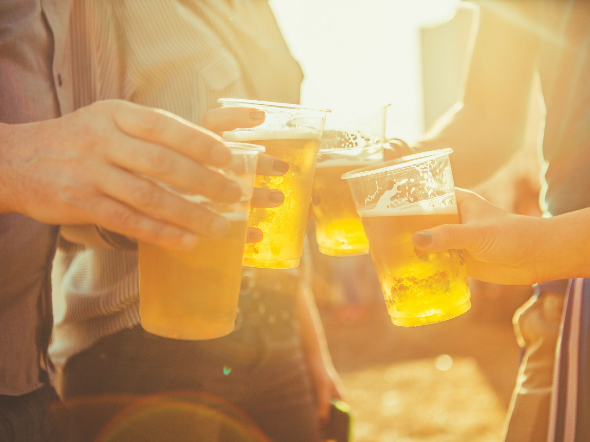 close up shot of hands toasting with beer. late afternoon with sunlight effect