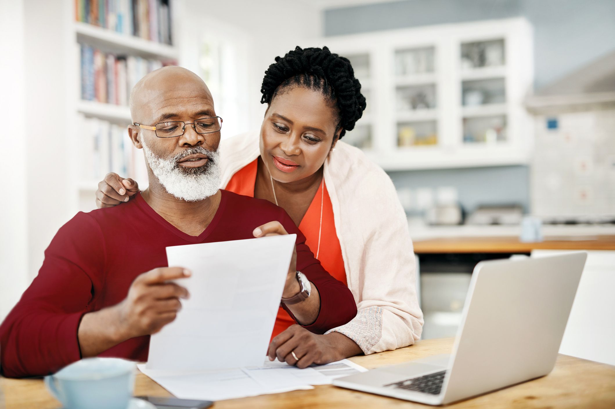 couple looking at documents together, laptop open in front