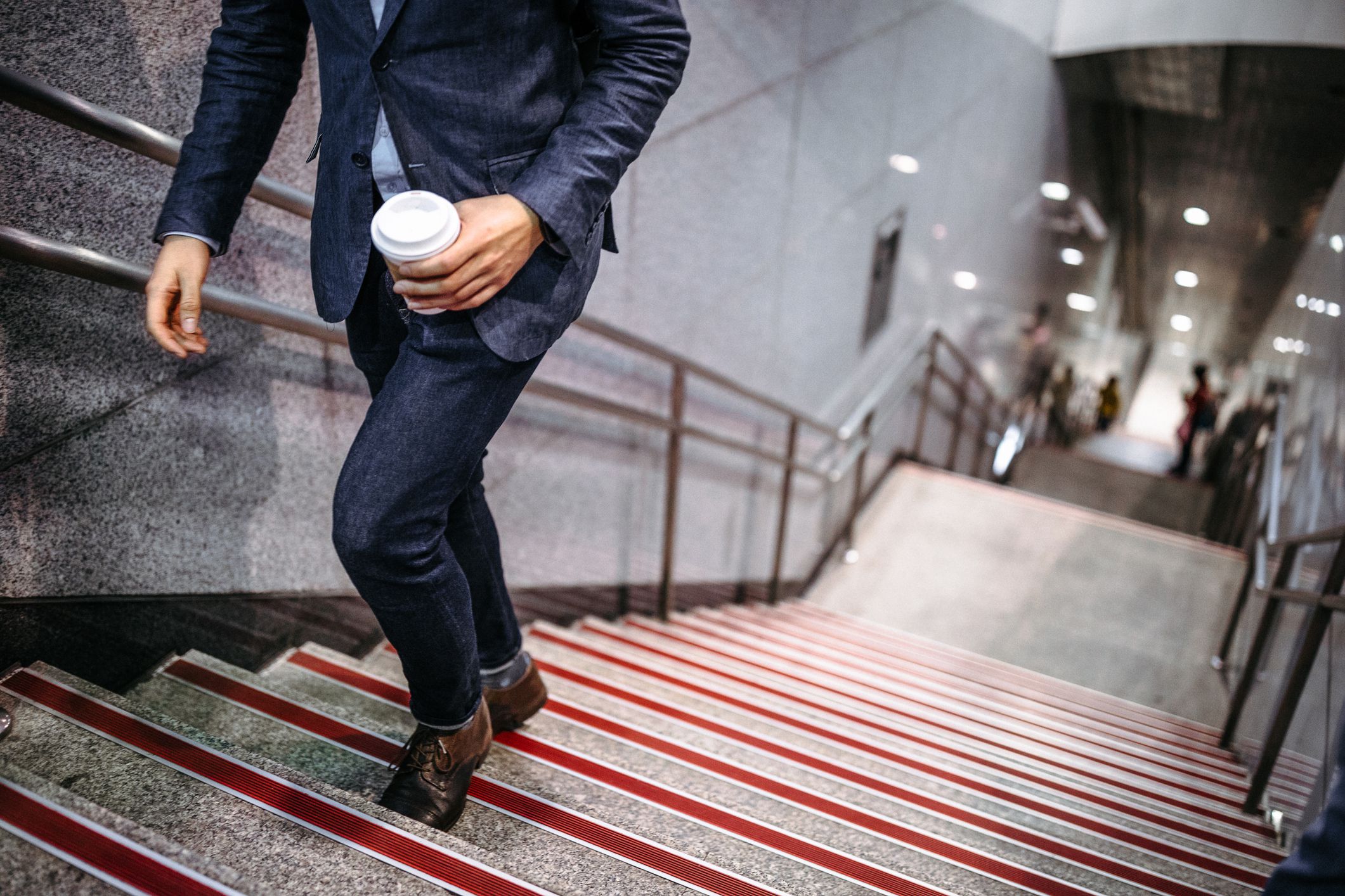 Modern businessman walking up stairs with coffee