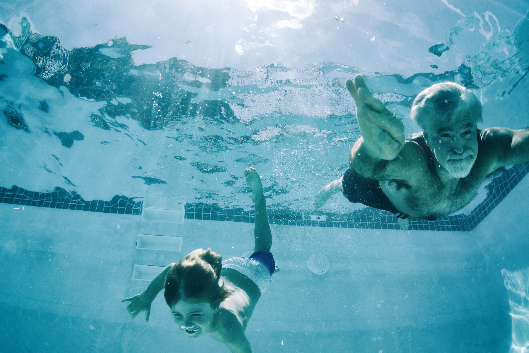senior man and small boy swimming in pool